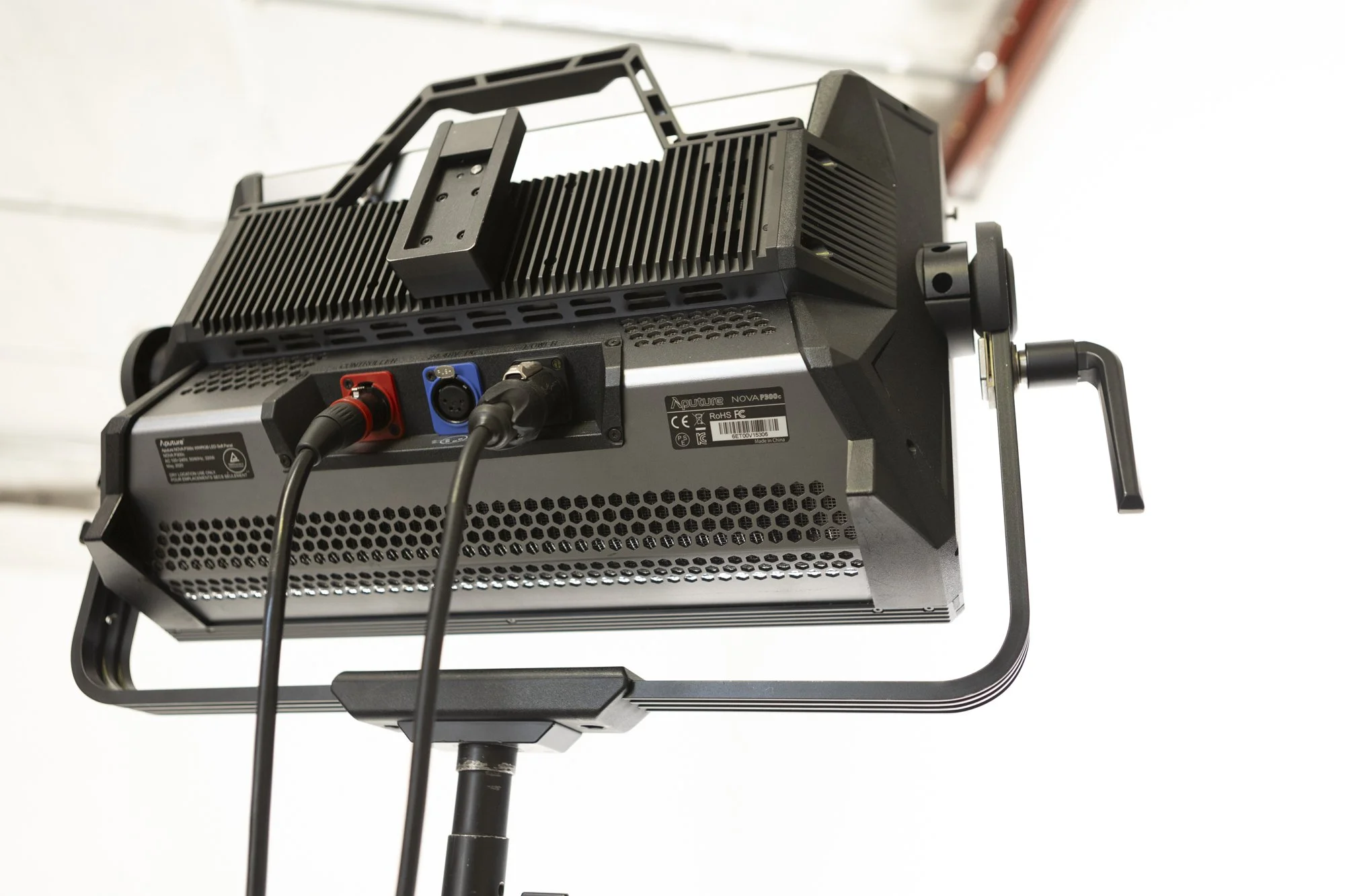A professional stage or studio LED light fixture mounted on a stand, with power cords plugged into the back.