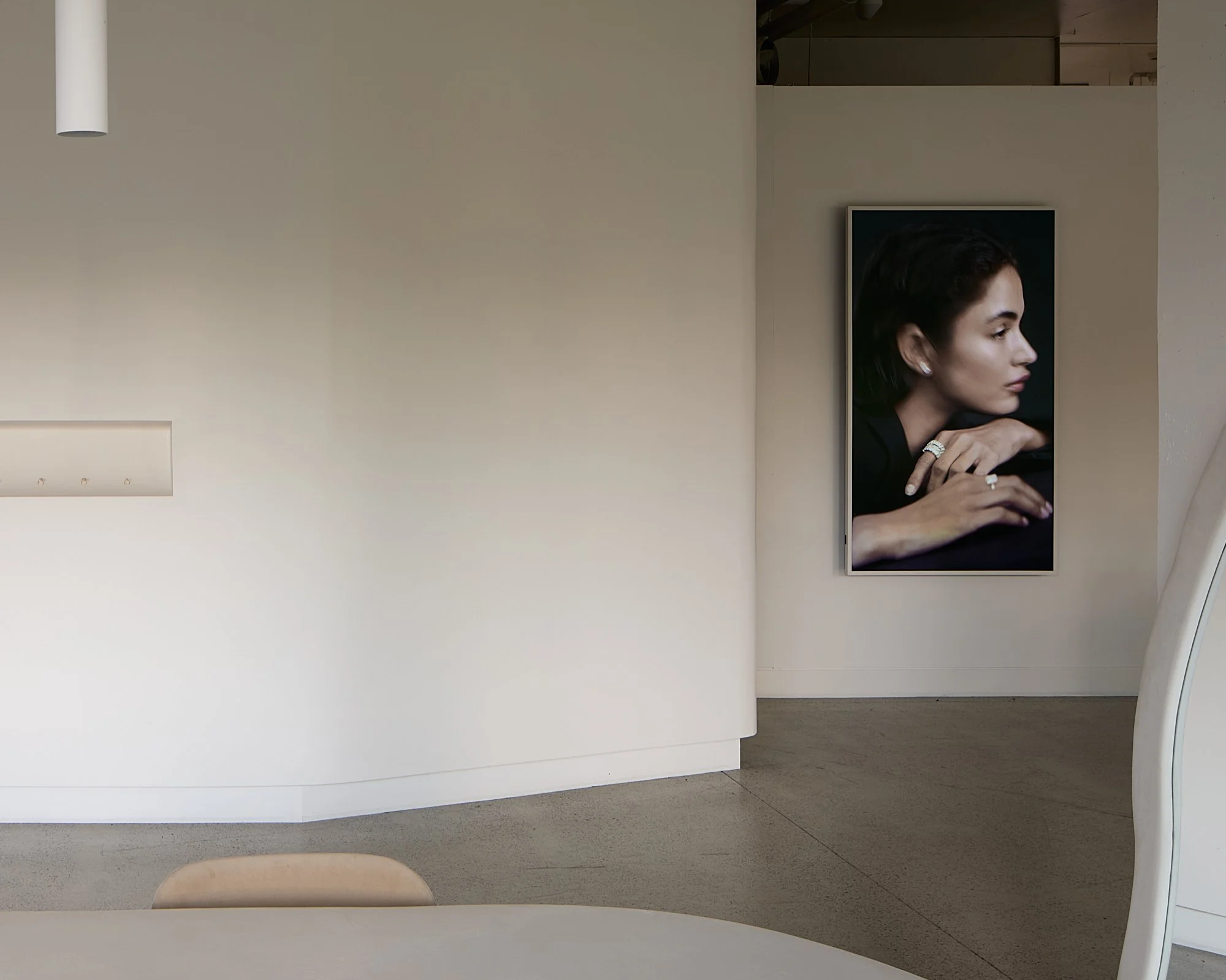 Modern interior space with a large portrait of a woman with dark hair, jewelry, and a contemplative pose hanging on the wall.