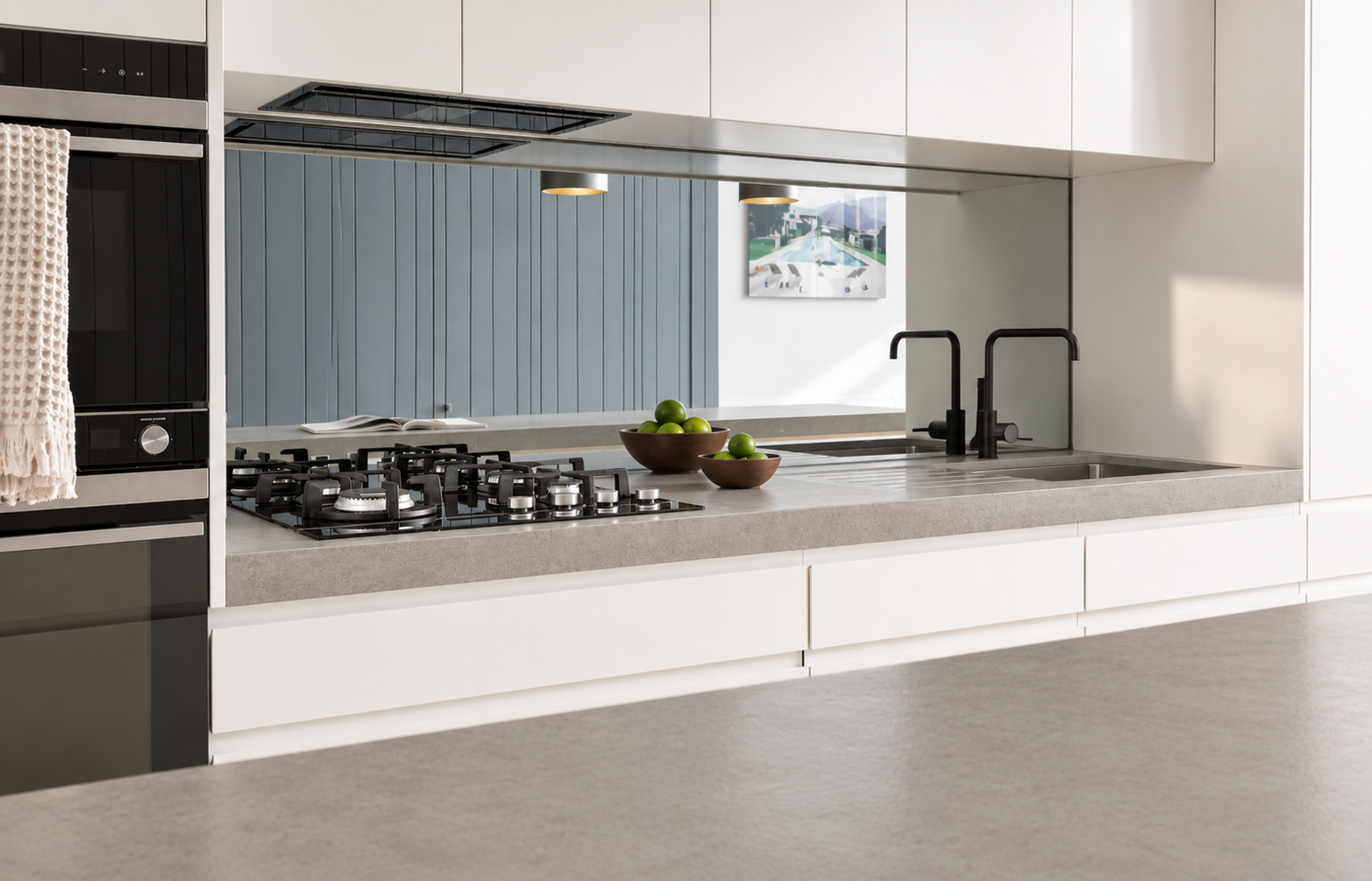 Modern kitchen with gray countertops, black faucets, and two wooden bowls filled with green apples on the counter.