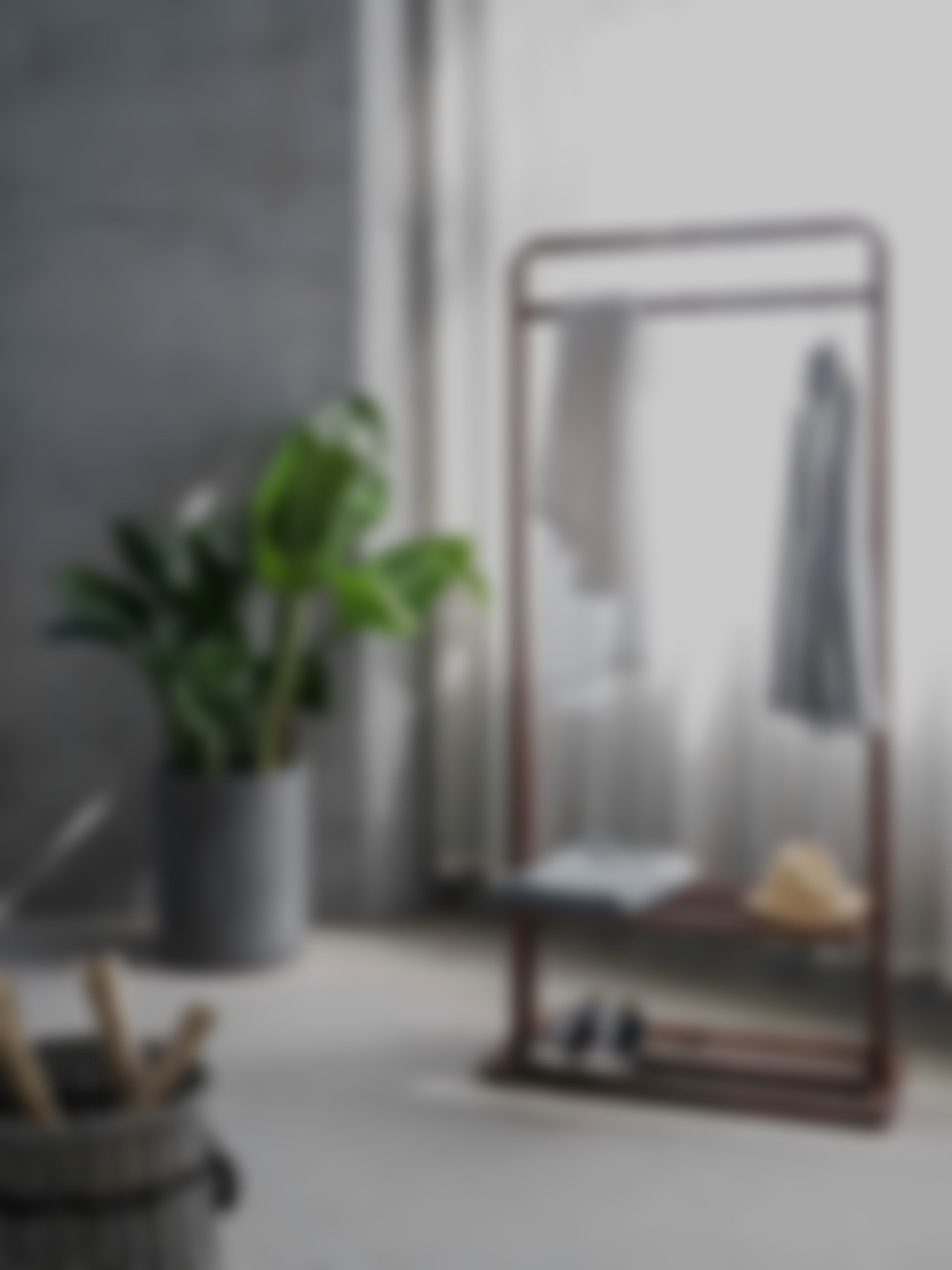 A blurred image of a modern interior with a potted plant, a bathroom or vanity mirror, and some folded towels.