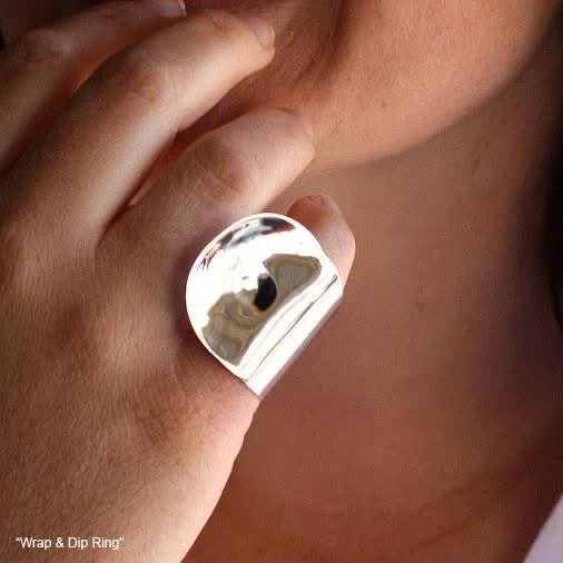 Close-up of a hand holding a shiny silver ring near a person's face.