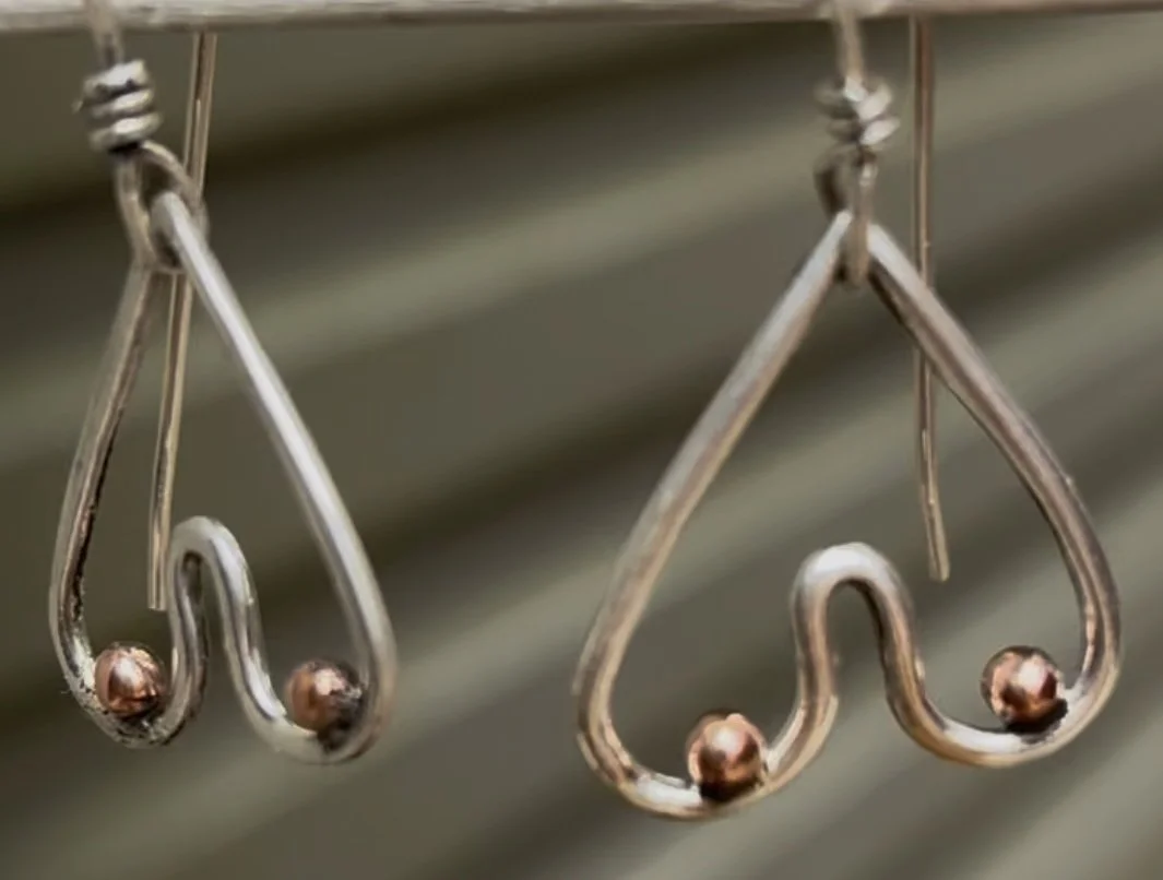 Close-up of two metallic coat hangers hanging on a rack.