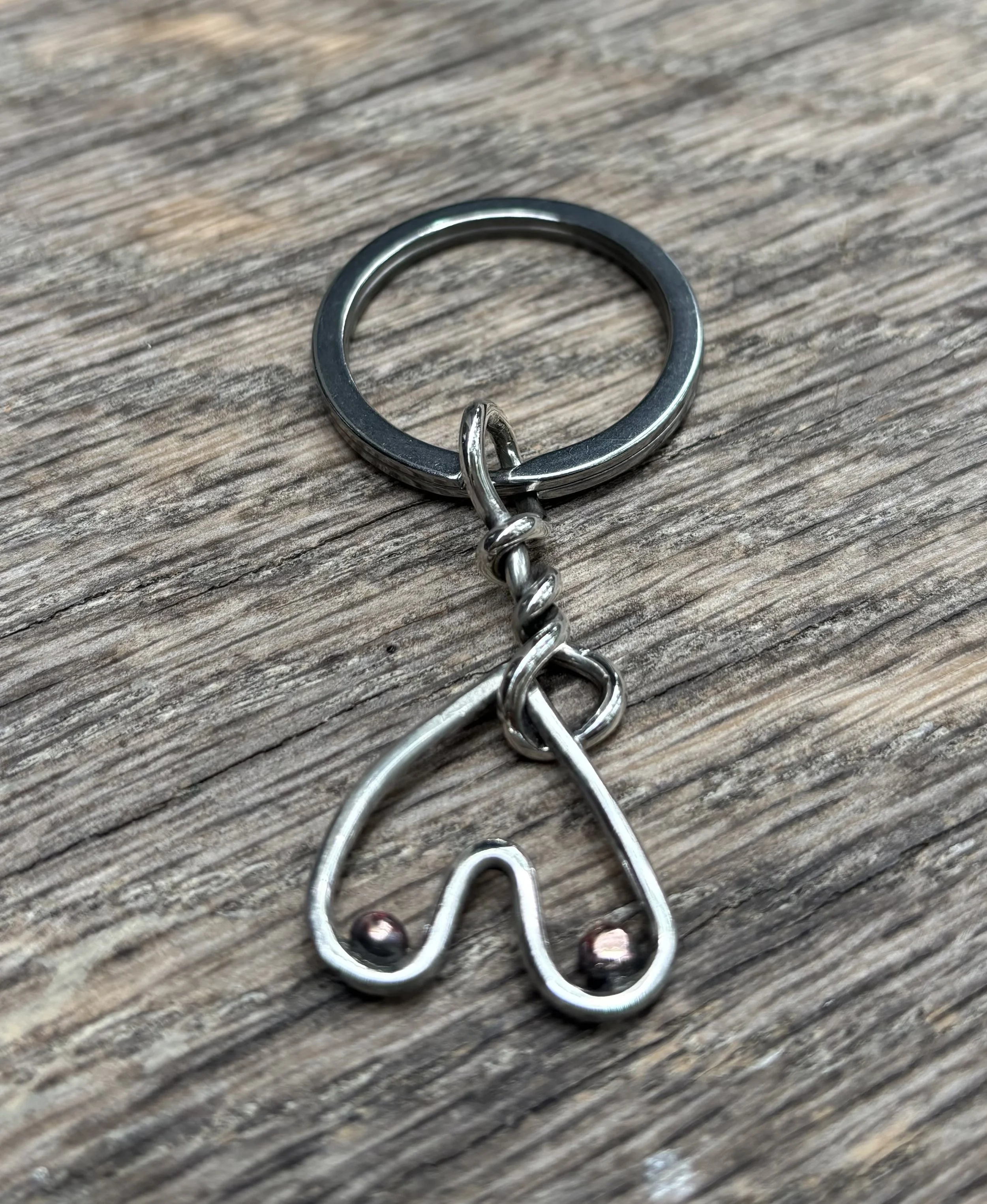 A close-up view of a metal keychain with a spiral design on a wooden surface.
