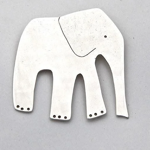 A white, elephant-shaped paper cutout with four legs and a trunk, placed on a gray surface.