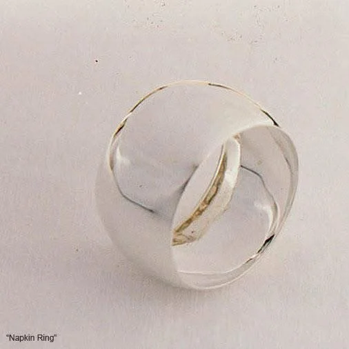 A silver napkin ring with a simple, smooth design, lying on a plain white surface.