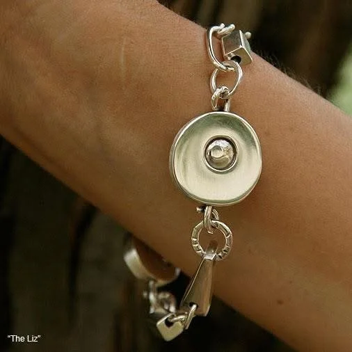 Close-up of a bracelet featuring a retractable metal badge reel and chain links, worn on a person's wrist.