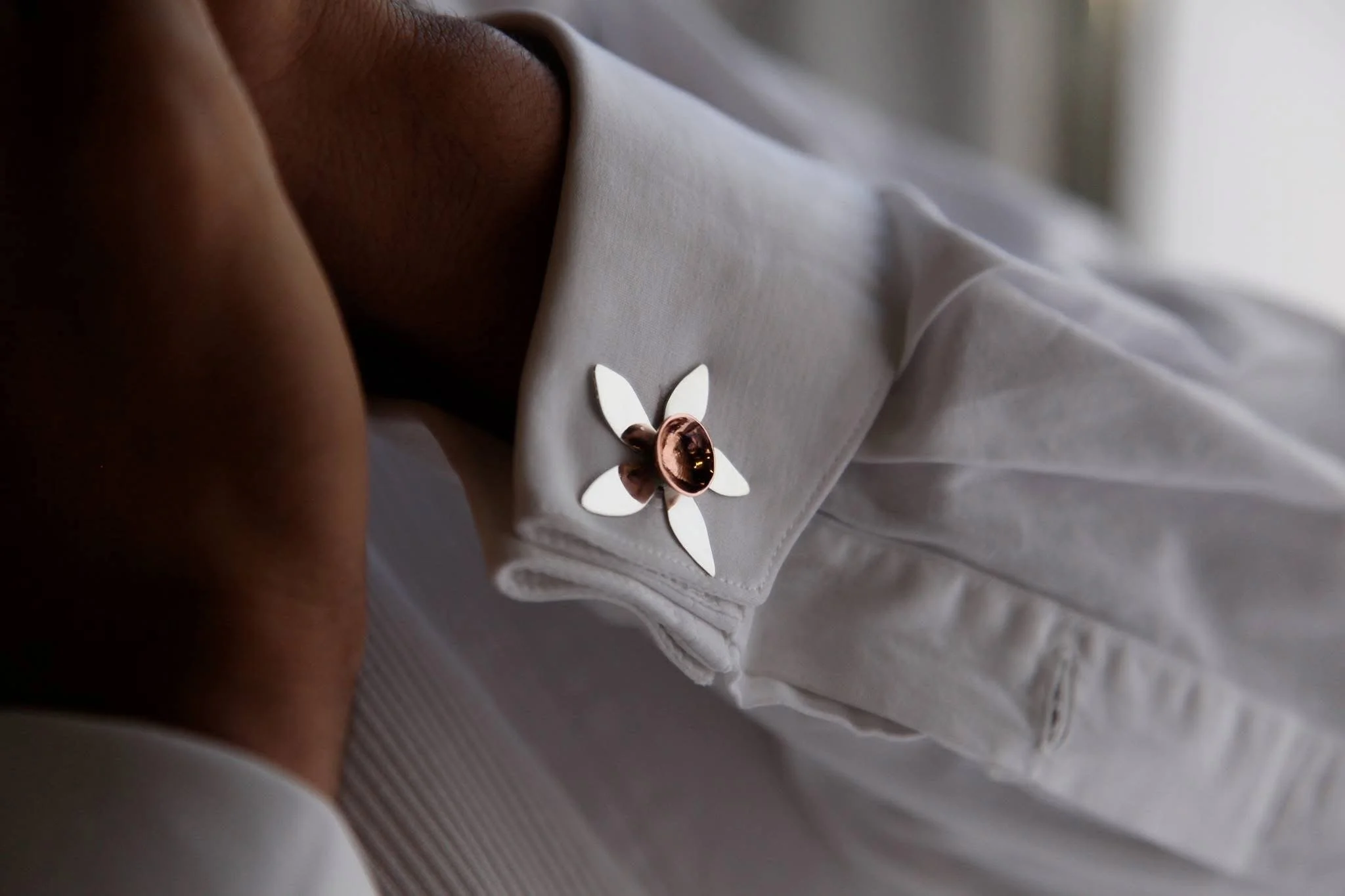 Close-up of a white fabric with a decorative flower-shaped embellishment that has white petals and a metallic center.