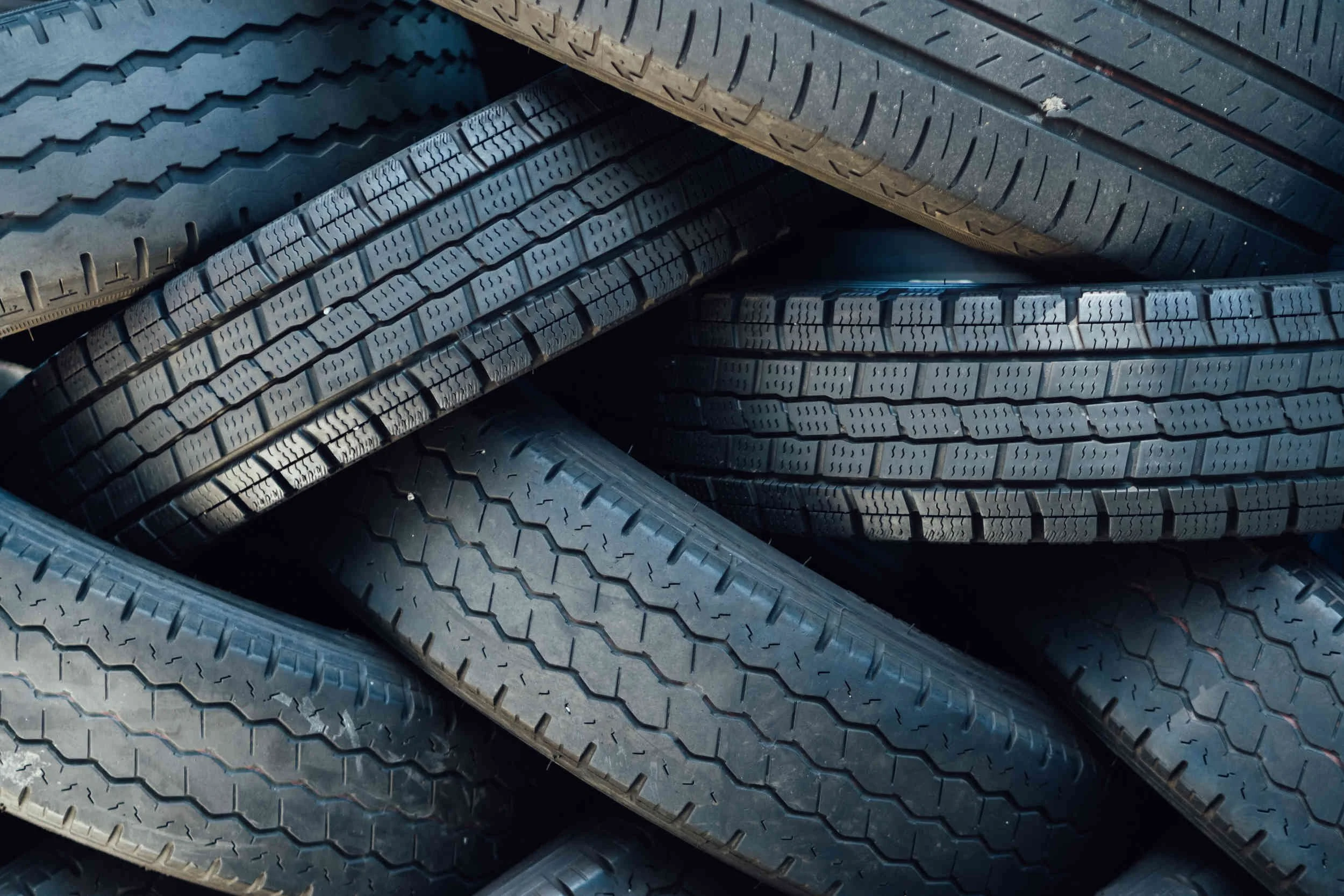 Close-up of several black tires stacked on top of each other, showing the tread patterns.
