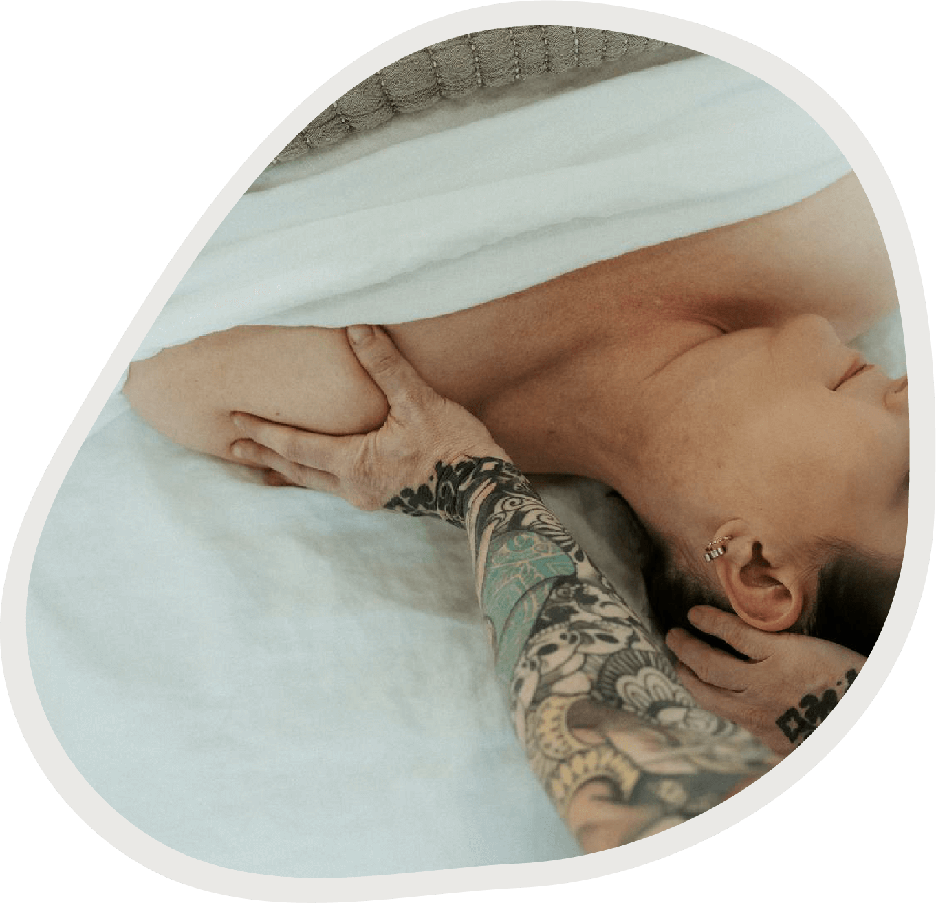 Massage therapist performing a shoulder and neck massage on a client lying on a treatment table.