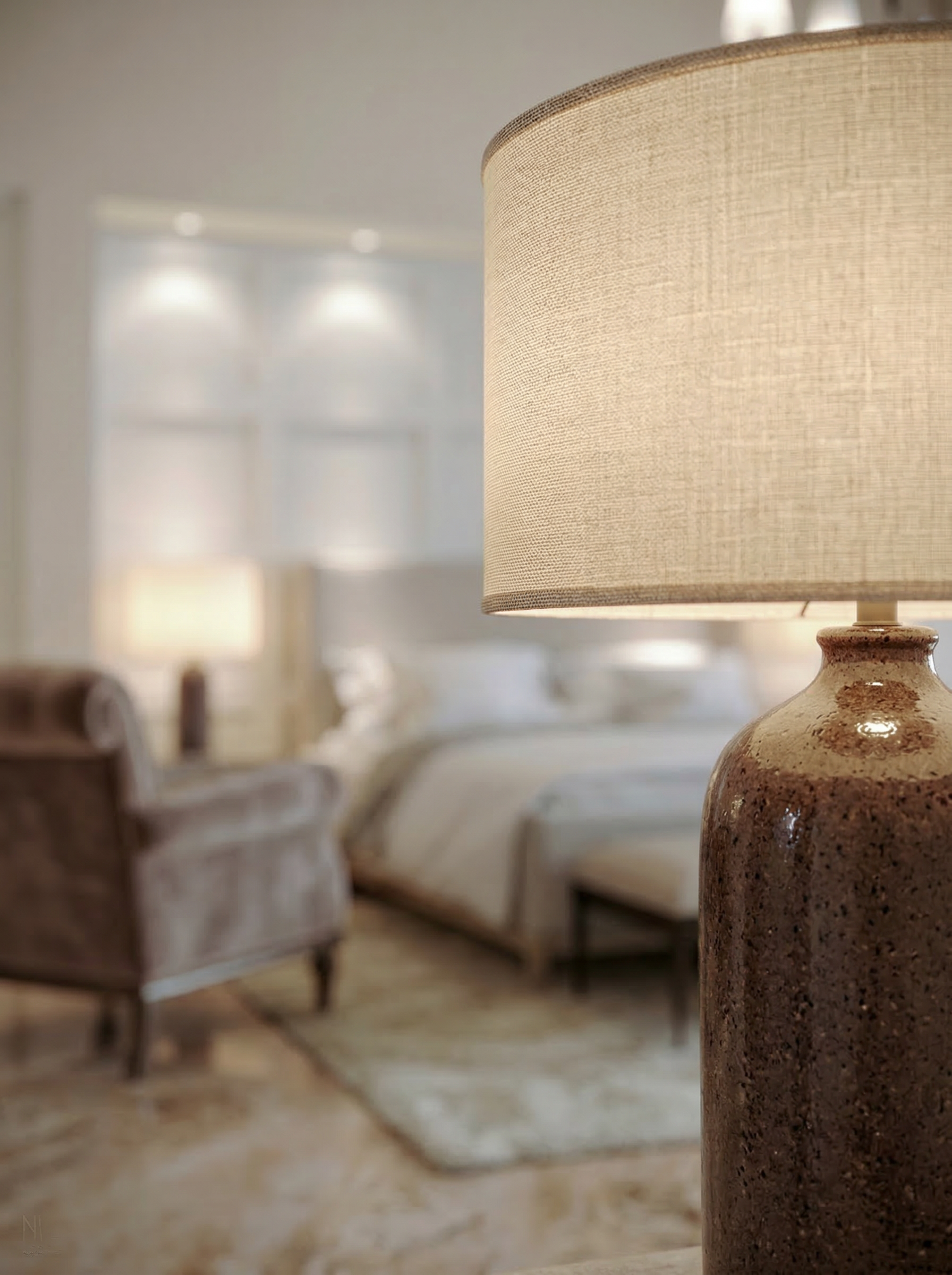 Close-up of a beige table lamp with a textured ceramic base, with a blurred living space featuring a sofa, armchair, and large windows in the background.