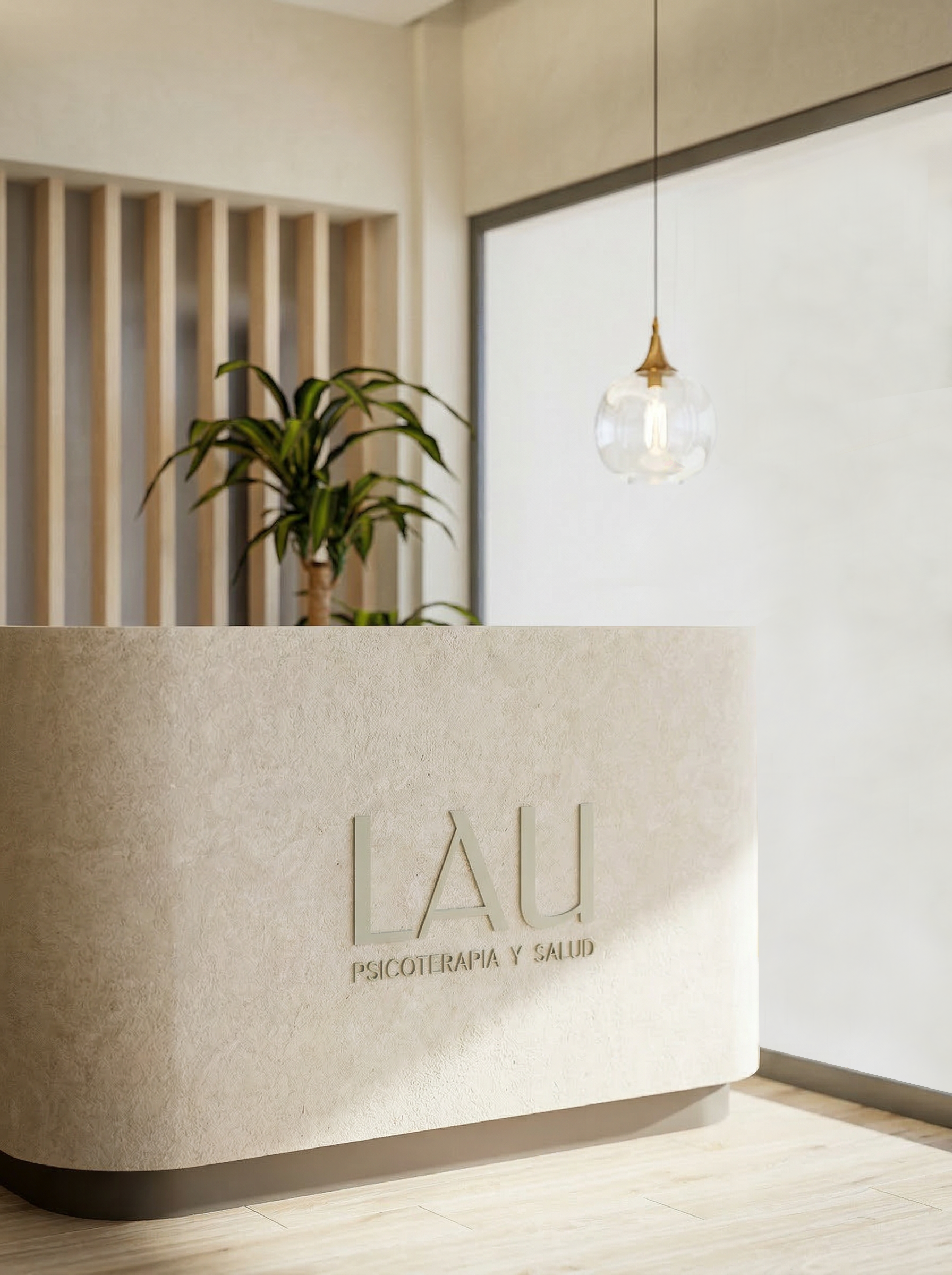 Reception desk in a wellness center with the words 'LAU Psicoterapia y Salud' on it, a potted plant, a hanging glass lamp, and a window letting in natural light.