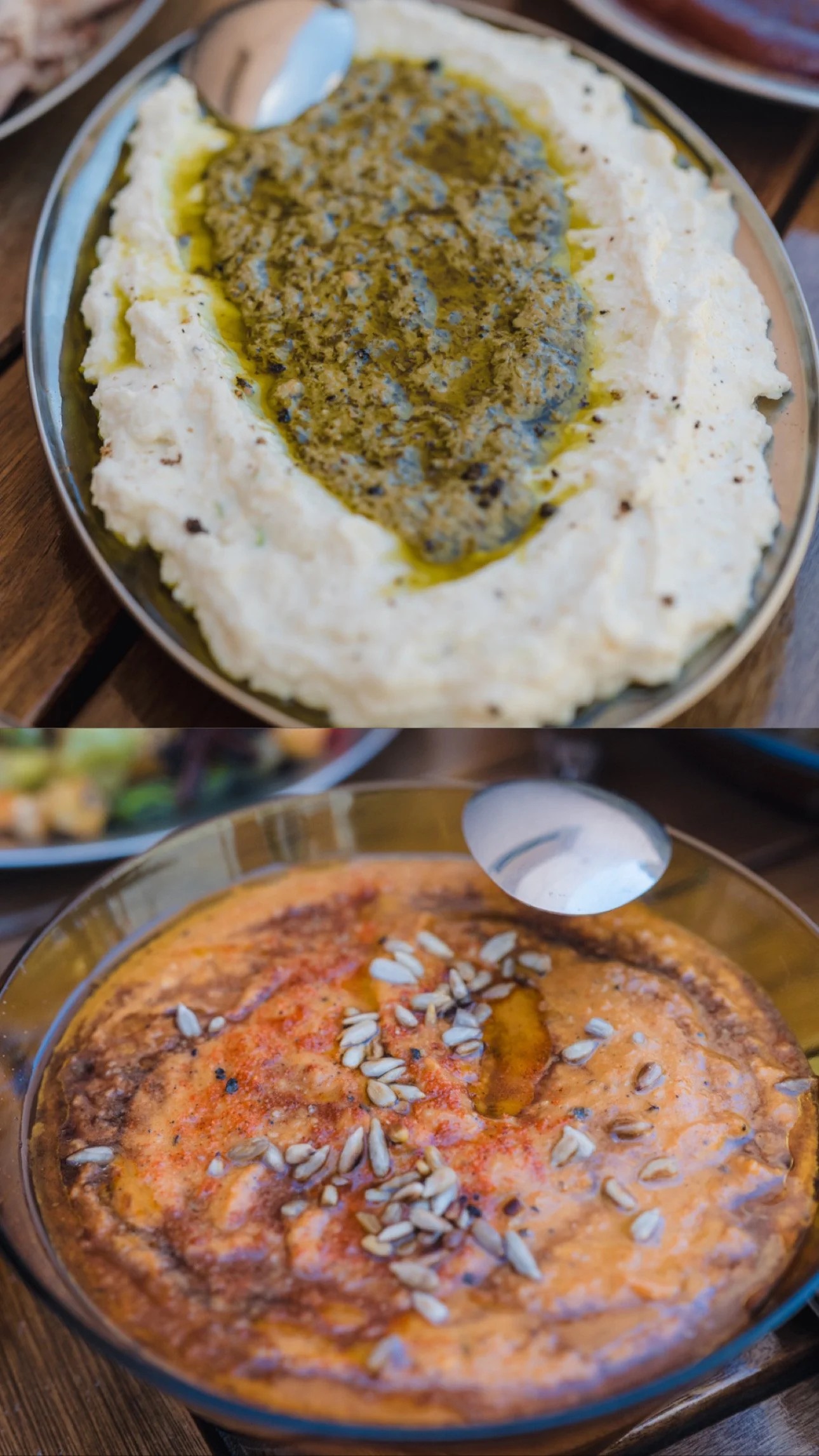 Two dishes on a wooden table: the top dish is a creamy spread with green pesto on top, the bottom dish is a pink-colored dip garnished with sunflower seeds and a drizzle of oil.