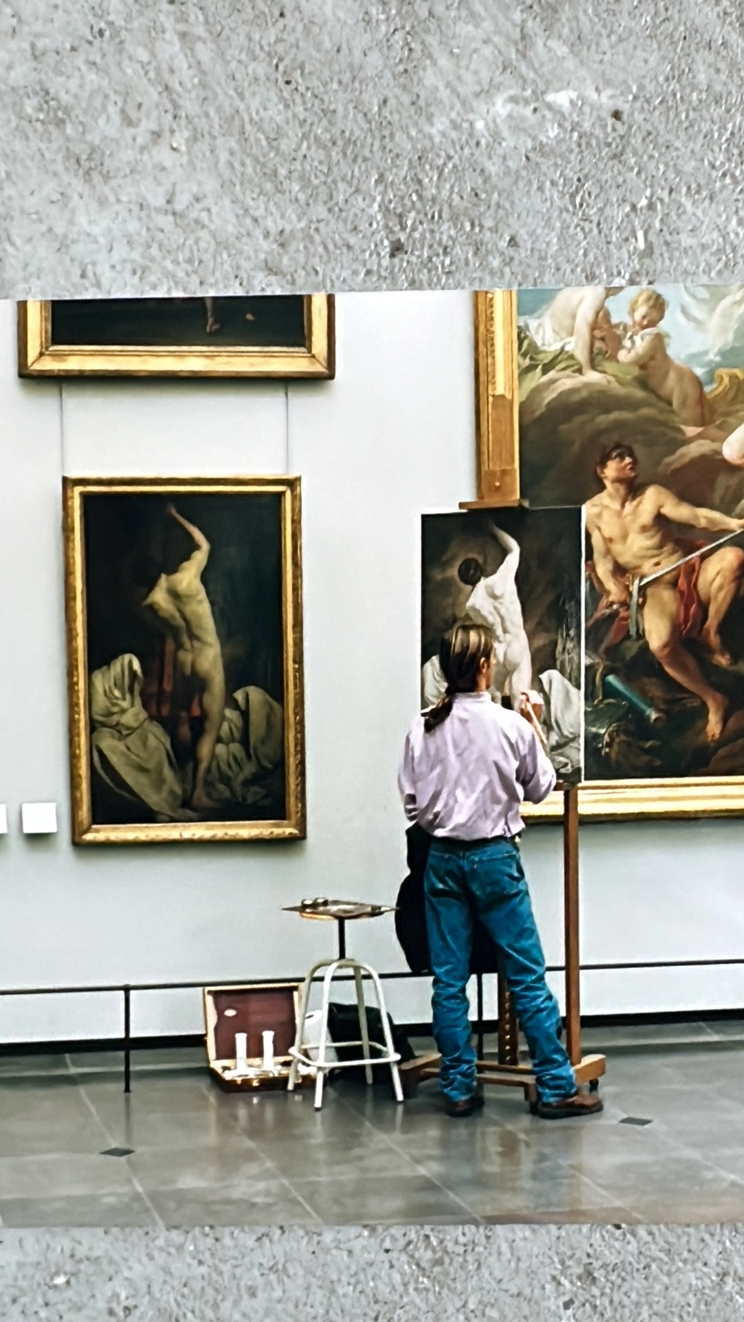 Chevalet installé dans une salle du Louvre, un artiste contemporain poursuit la tradition des copistes en étudiant les chefs-d’œuvre des maîtres anciens.