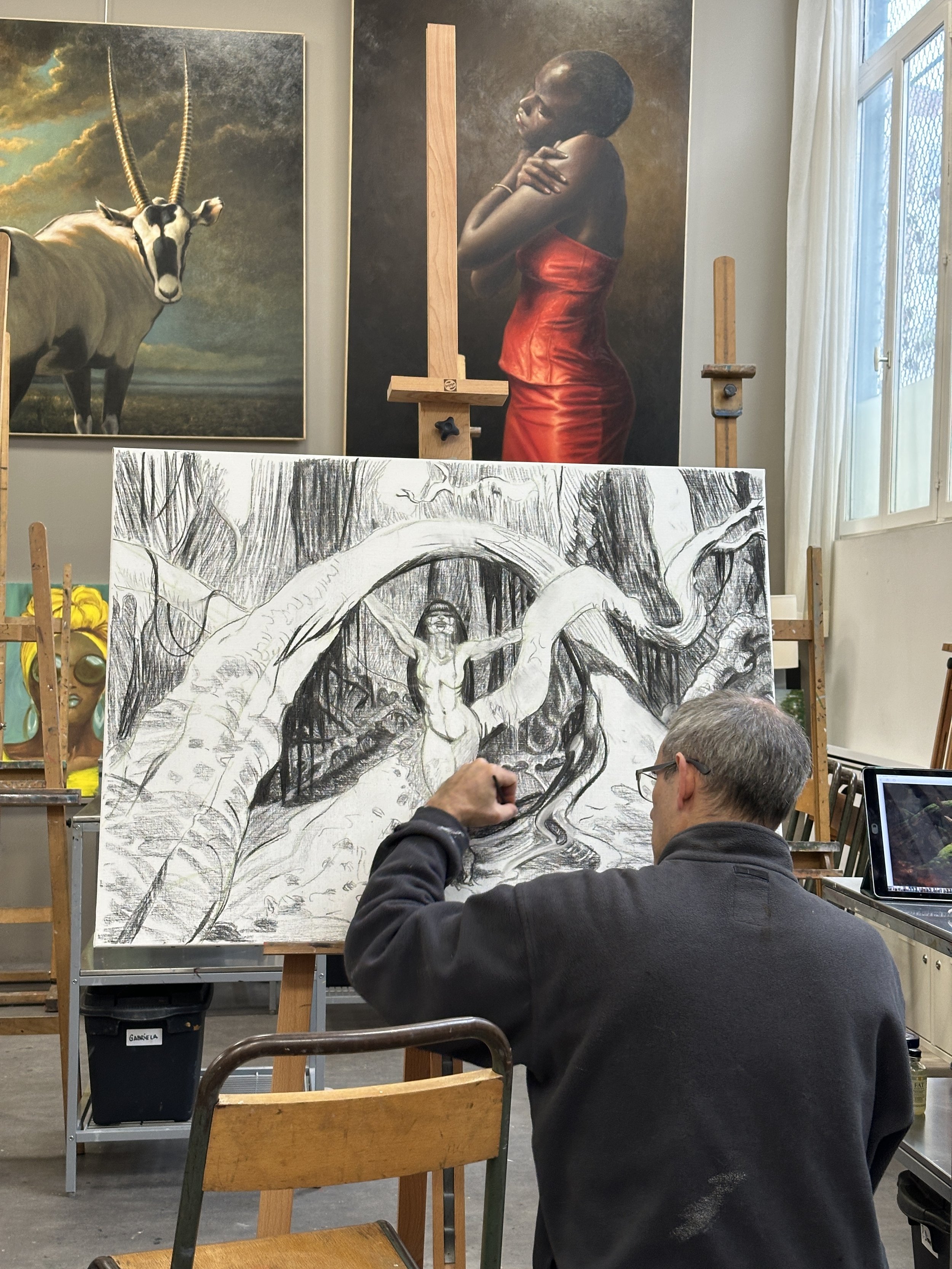 Un élève adulte dans l'atelier de cours d'illustration et dessin de Montreuil en train de réaliser un dessin fantastique inspiré des comics avec la technique du fusain et encre de chine.