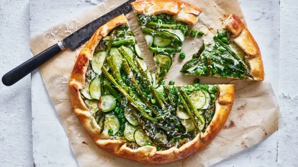 Vegetable tart with green vegetables including asparagus, spinach, and zucchini on a Short Crust pastry , with one slice removed.