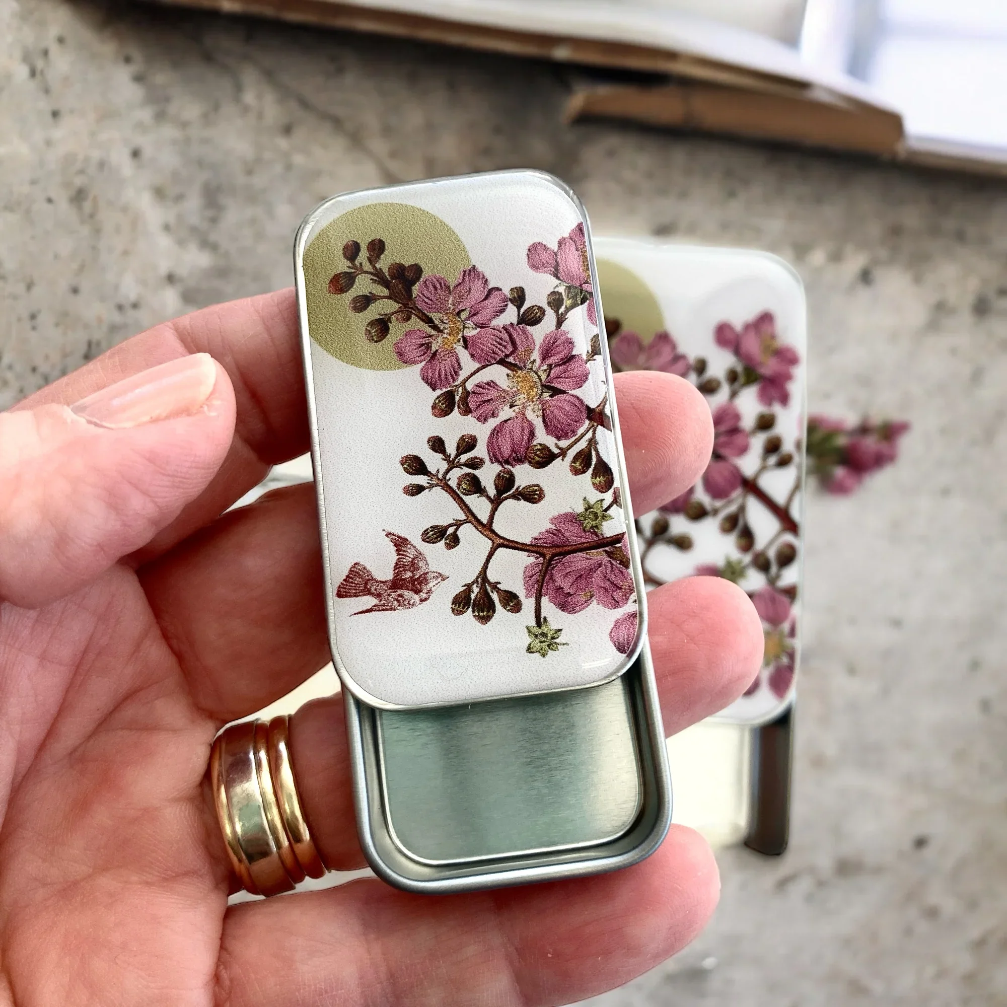 Cherry Blossom and Swallow Notions Tin by Firefly Notes featuring a delicate floral design and a graceful bird on a handcrafted resin-topped sliding tin.