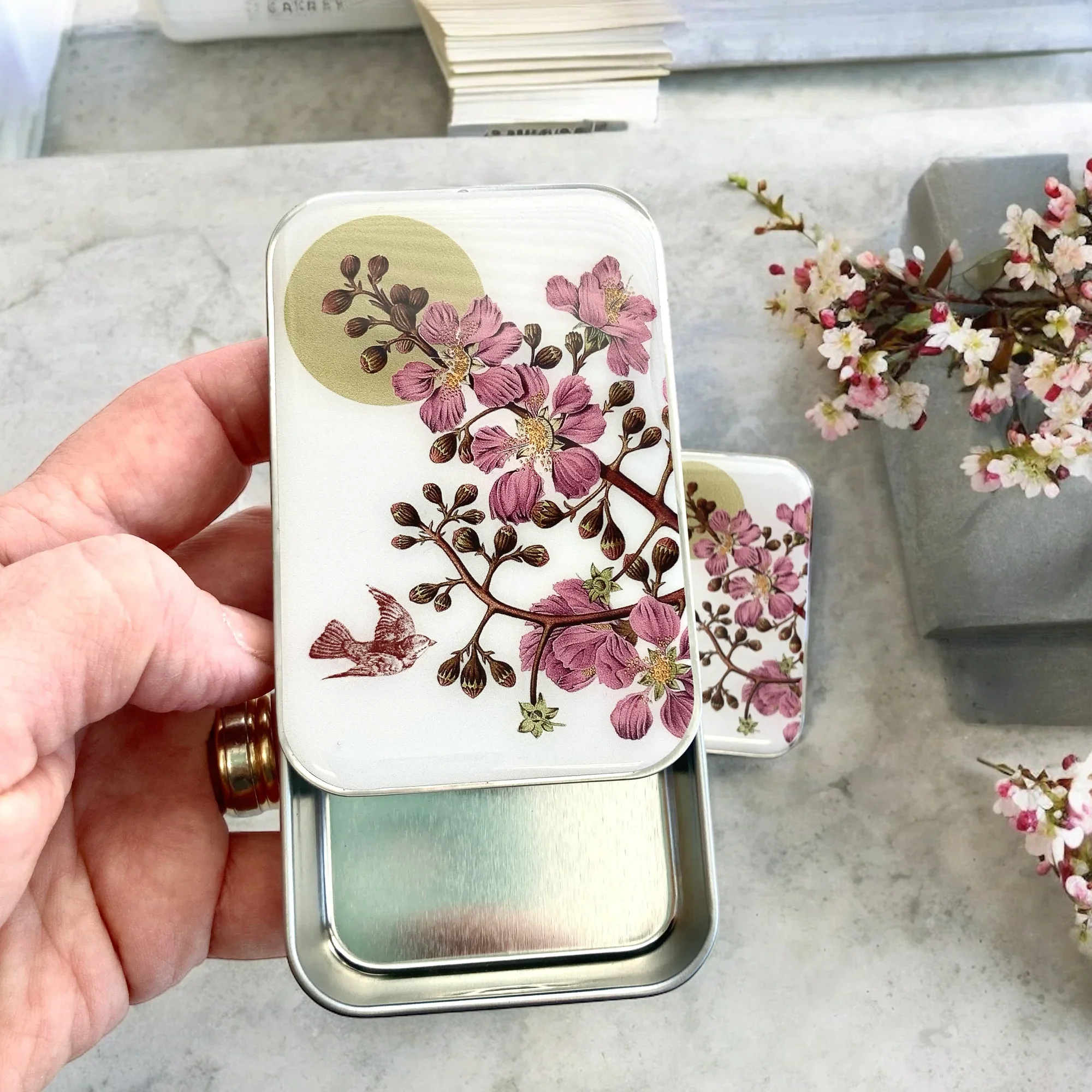 Cherry Blossom and Swallow Notions Tin by Firefly Notes featuring a delicate floral design and a graceful bird on a handcrafted resin-topped sliding tin.