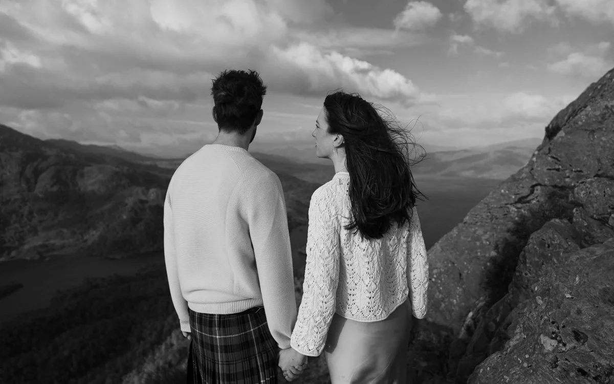 A fashionable couples photograph looking into the distance from the mountains, 