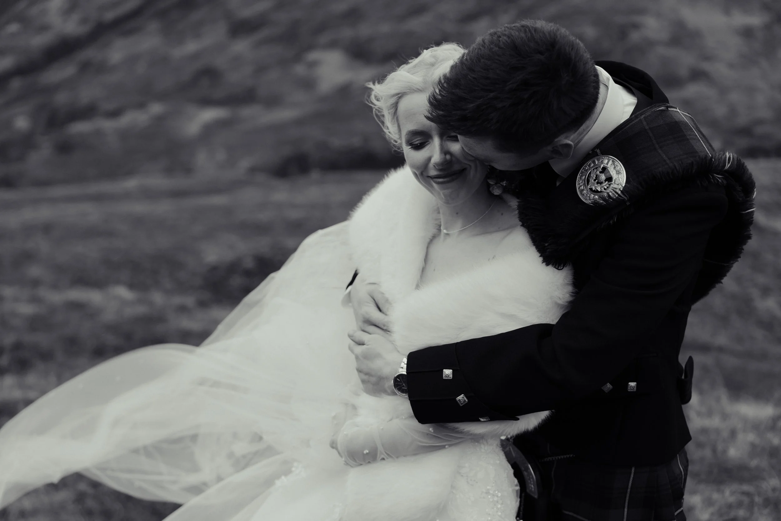 A romantic vintage photograph of groom embracing the bride in wintery wild mountains of Scotland