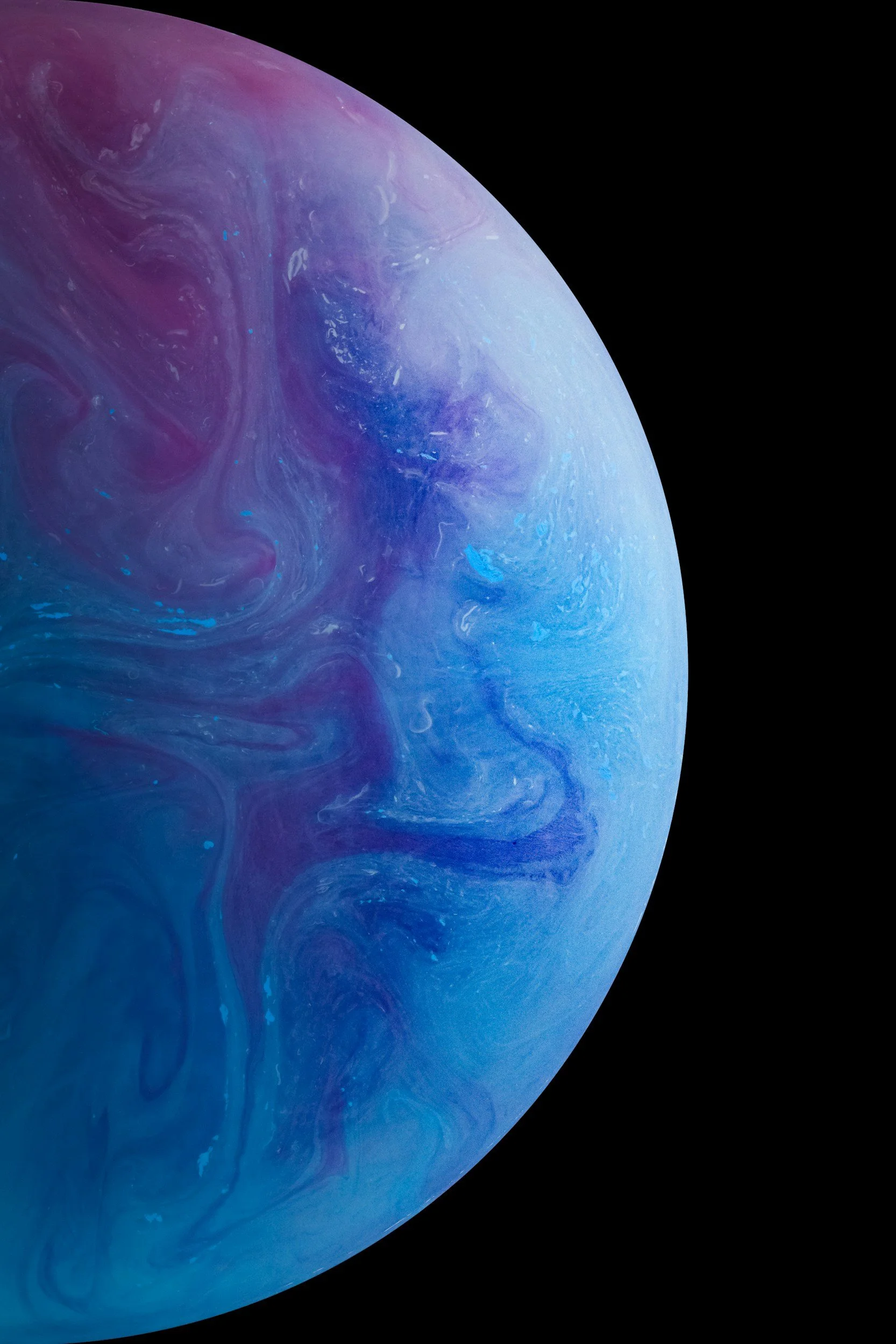 Färgglad planetliknande bild med blå, lila och rosa nyanser, delvis synlig mot svart bakgrund.