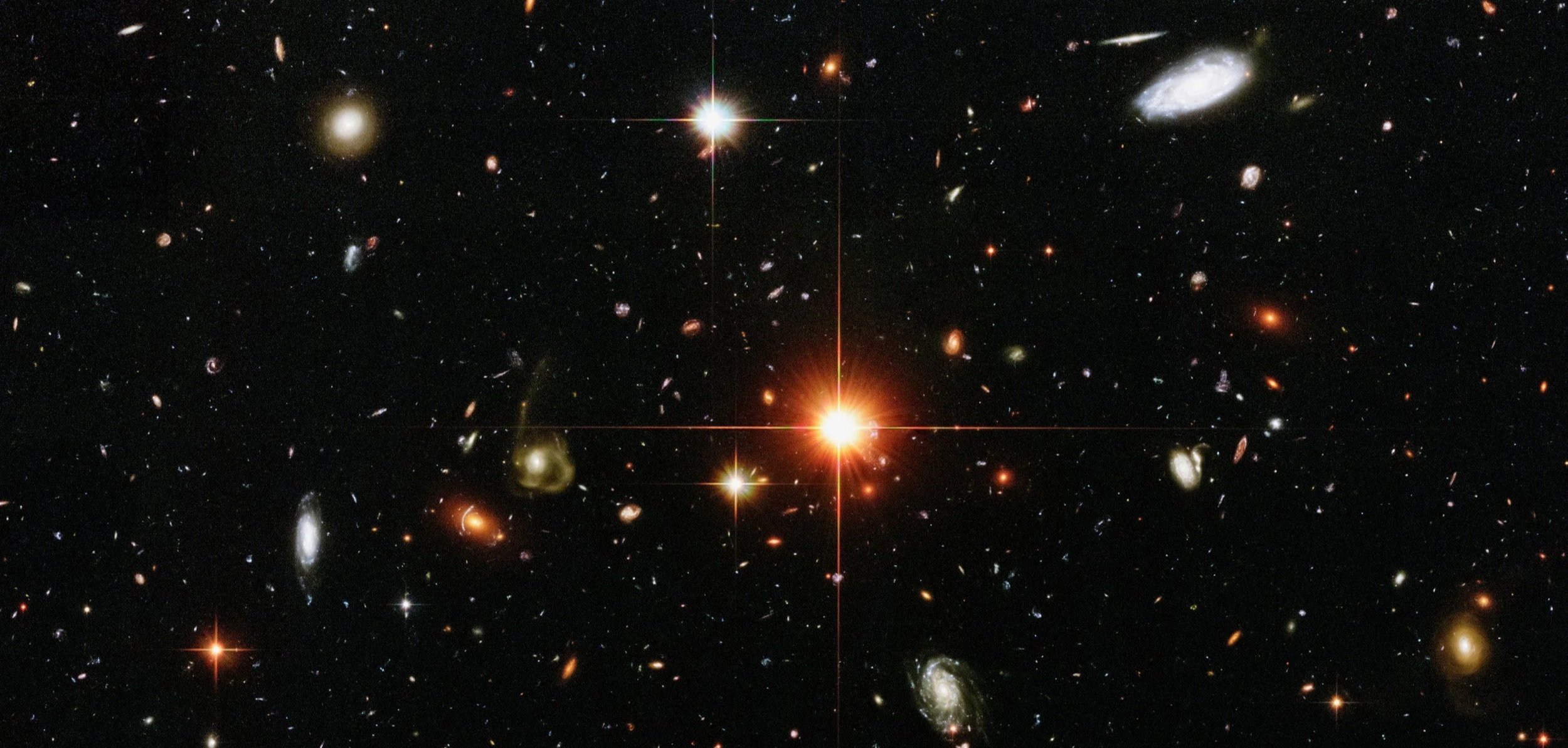 Bild av rymden med många olika galaxer och en ljusstark stjärna i mitten.