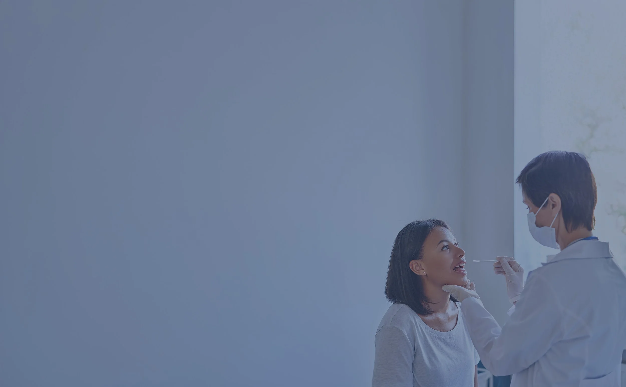 A woman is receiving a nasal swab test from a healthcare professional wearing a mask and gloves in a clinical setting.