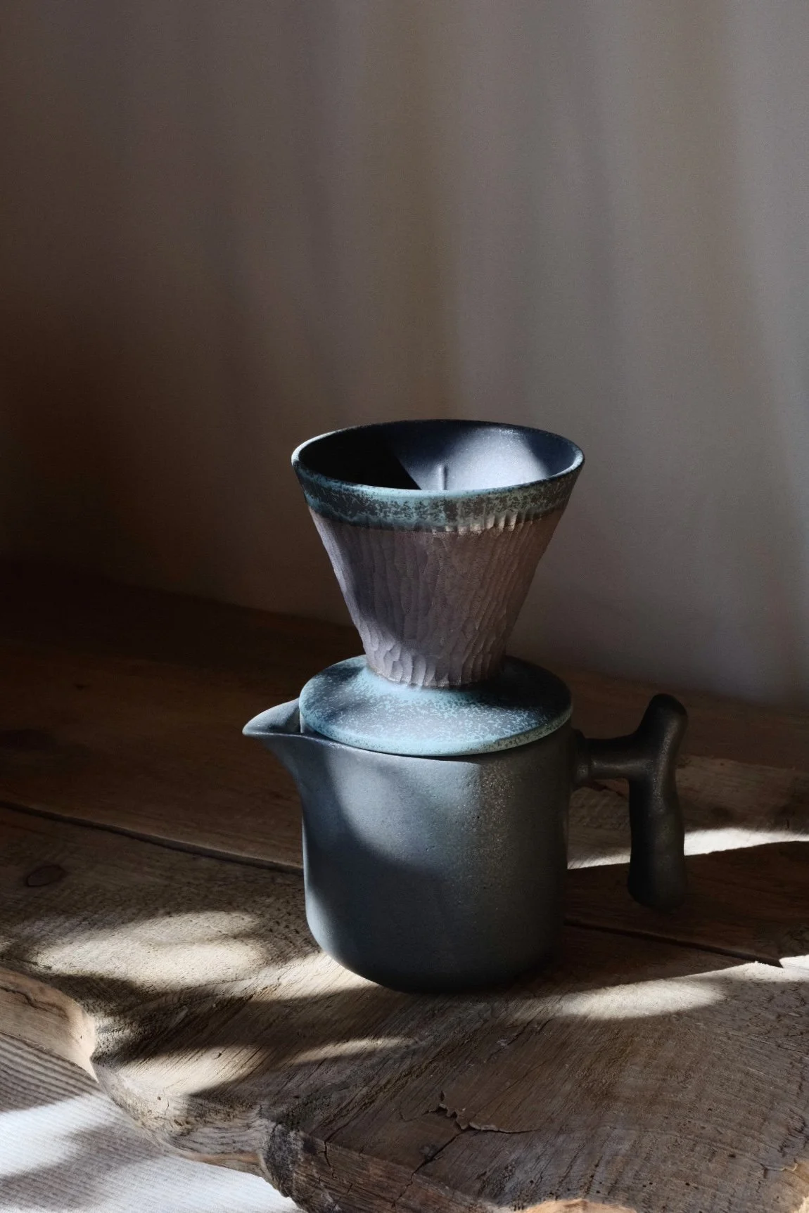 Person holding a textured black ceramic bowl, with three other textured ceramic bowls on a wooden surface in the background.