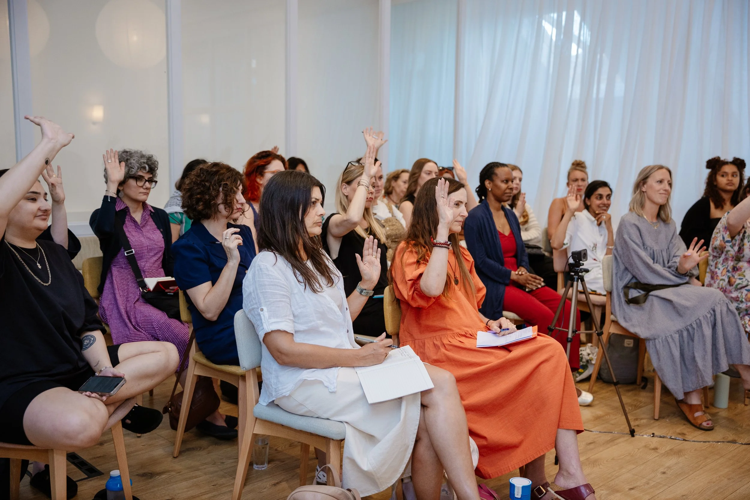 Women attending a seminar or conference, some raising their hands.