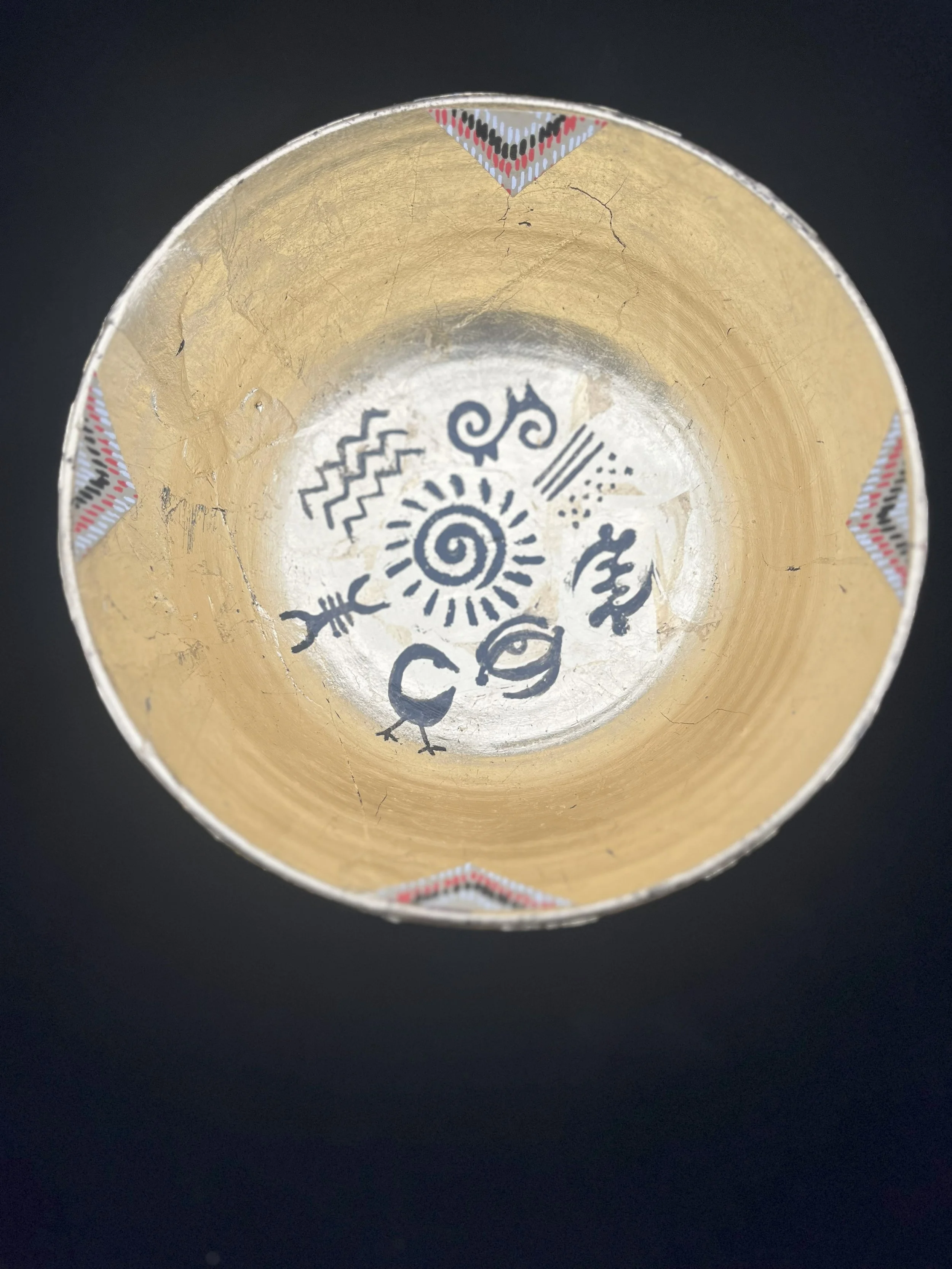 Title: Chalice I
Artist: Vincent Dion Stringer
Medium: Mixed Media Sculpture
Materials: Reconstructed ceramic bowl, candleholder stem, brass base; gold and silver leaf; Adinkra symbols; textile inlay (red, black, and metallic motif)

Description for 