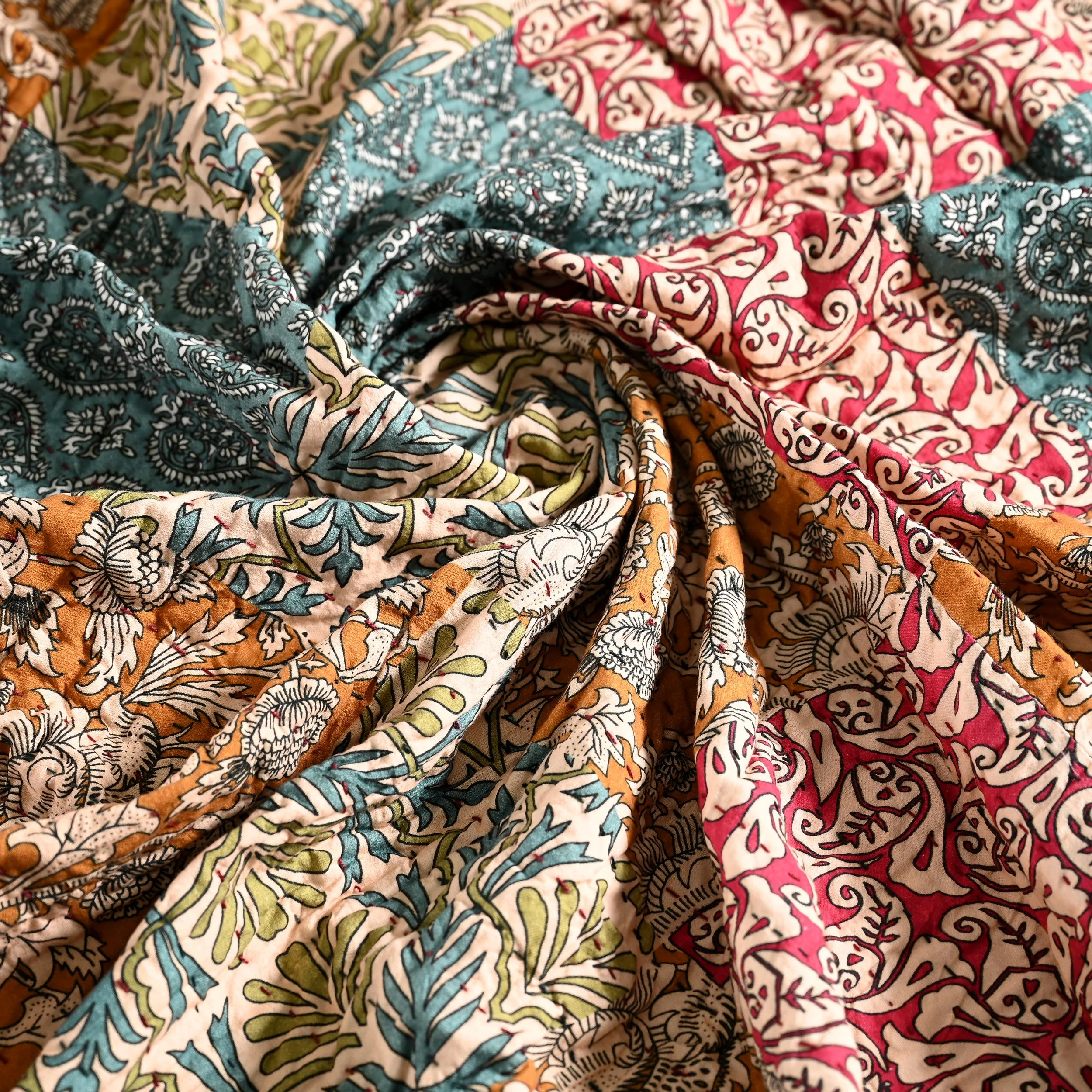 Close-up of multicolored patterned fabrics with intricate floral and leaf designs in shades of blue, pink, orange, and white.