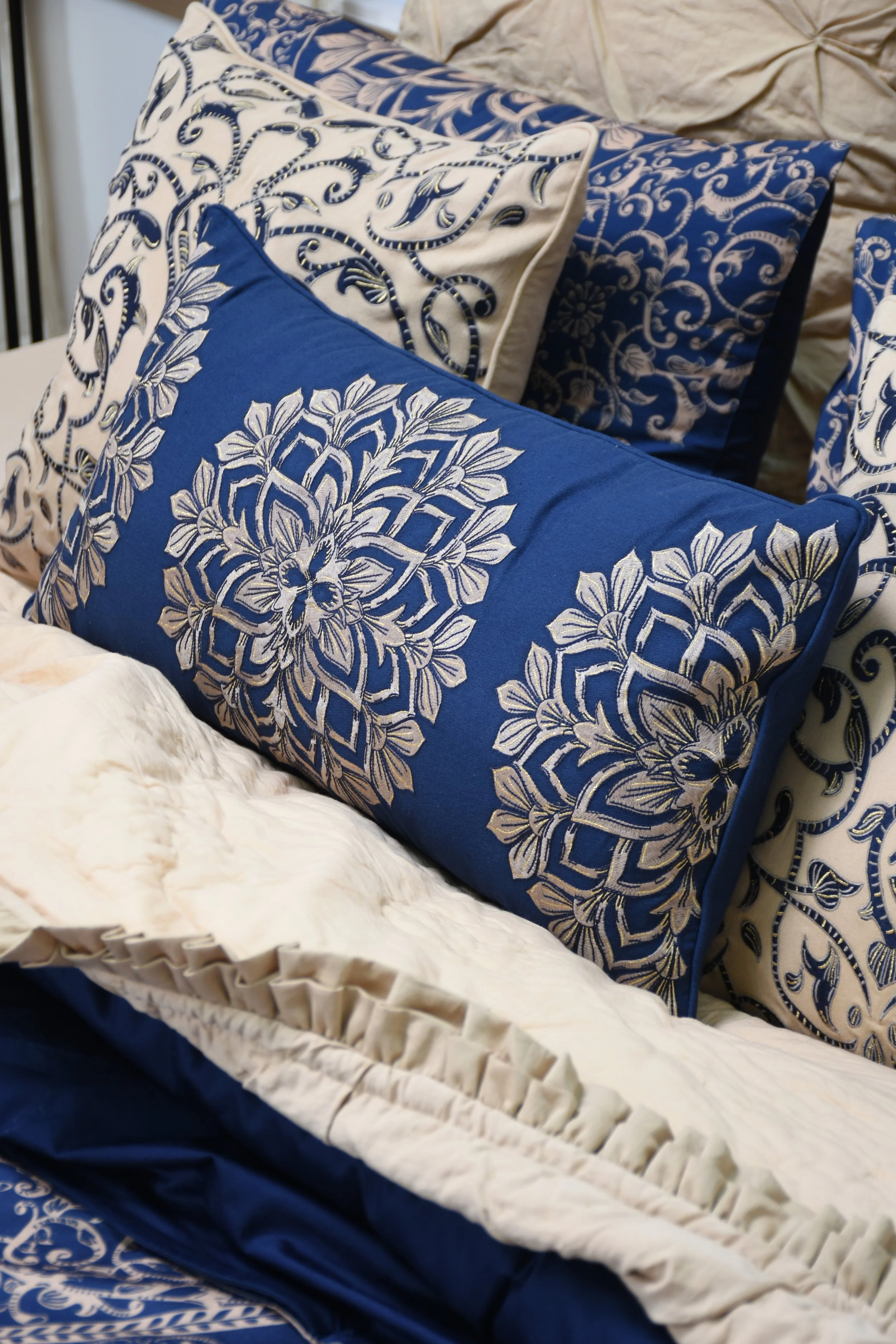 Close-up of decorative pillows with blue and white patterns, layered on a bed.
