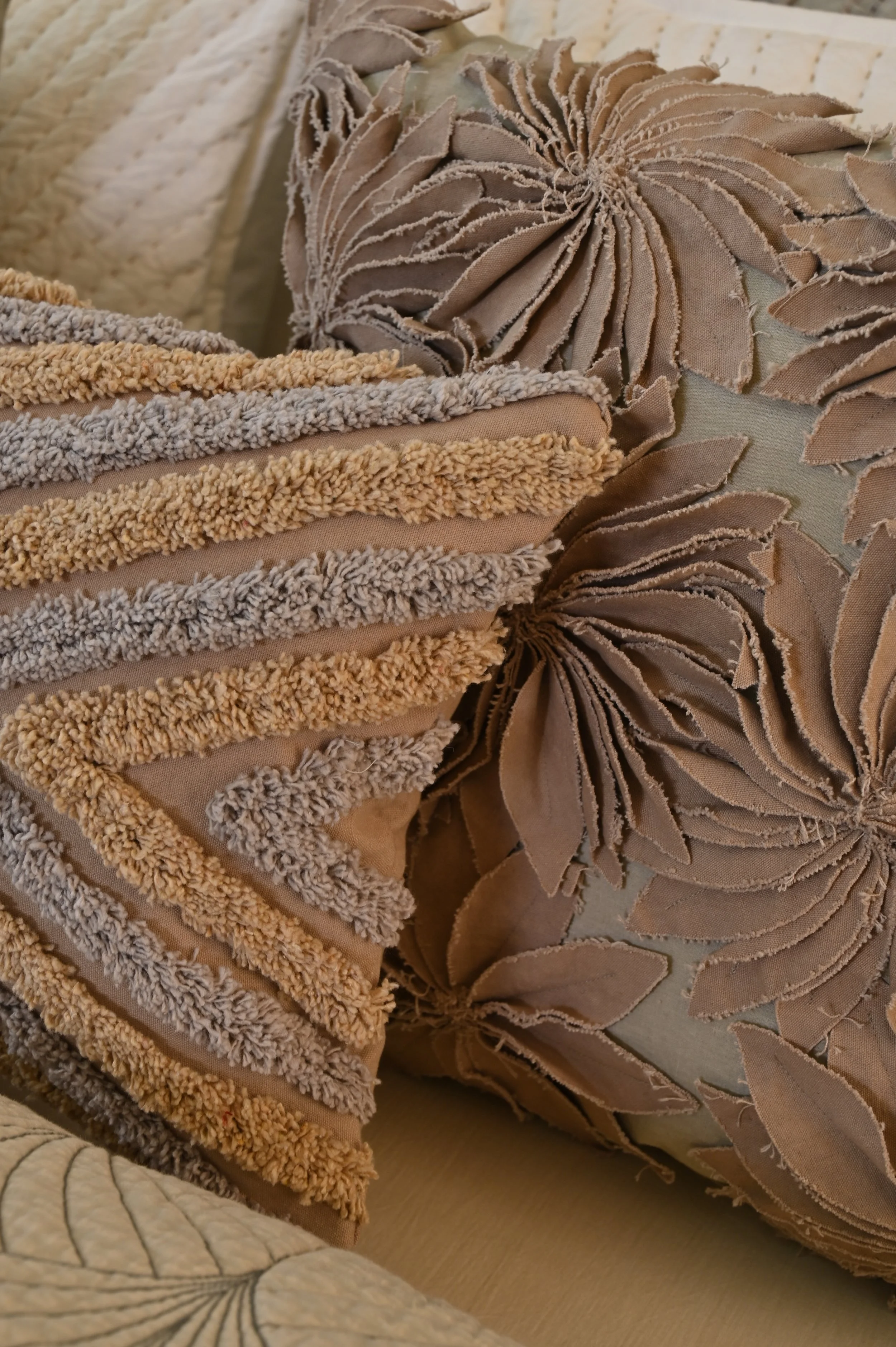 Close-up of decorative throw pillows with textured fabric and floral embroidery on a sofa.