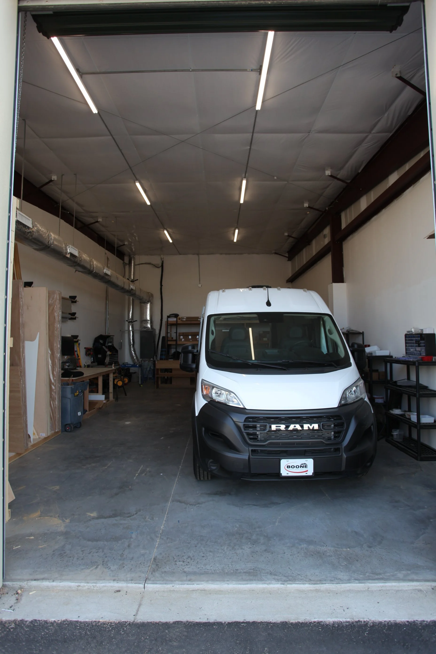 Vantra shop interior with a white Ram ProMaster van parked inside, tools, shelving, and workspace visible.