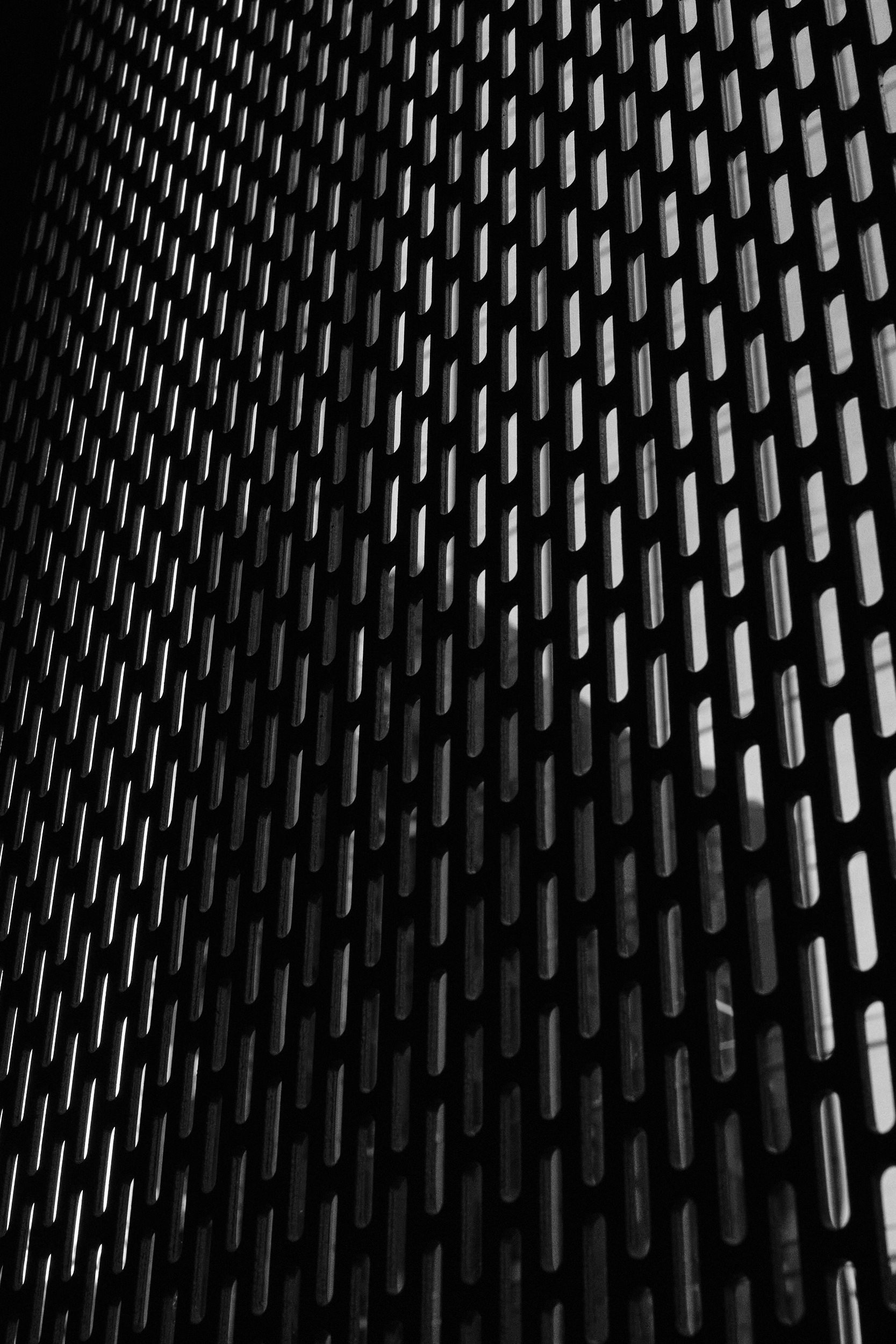 Close-up of a metal surface with a grid of rectangular openings, showing reflections of light.