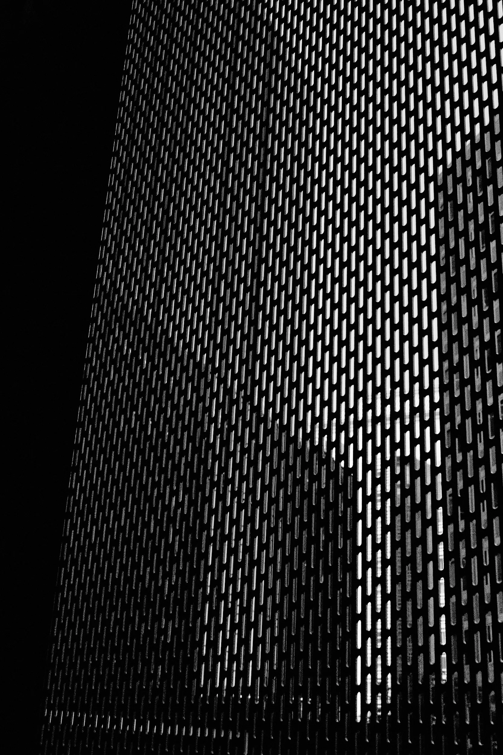 Close-up view of a perforated metal surface with evenly spaced elongated oval holes, creating a textured pattern.