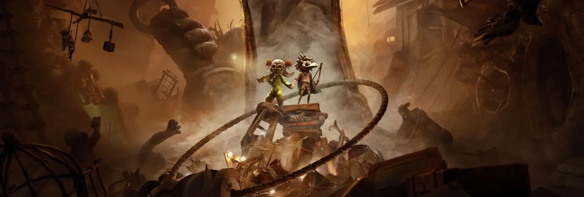 Two characters, dressed in adventure gear, standing on a pile of items amidst a chaotic, ruined environment with debris and twisted metal, holding hands in a smoky, fiery setting. They are the main characters from the Little Nightmares 3 co-op game.