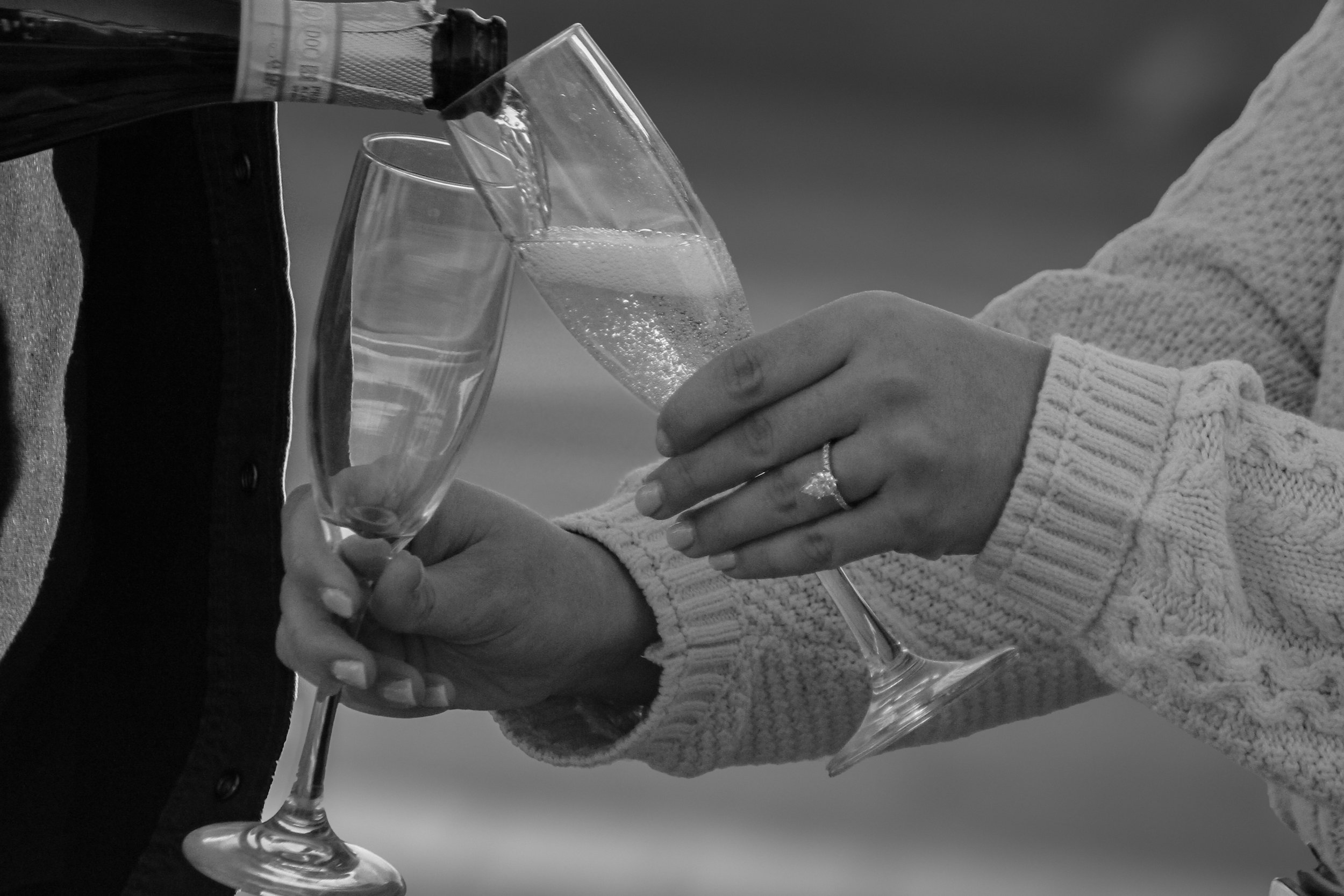 Young man sitting on grass beside rusty metal fence in a park during sunset.