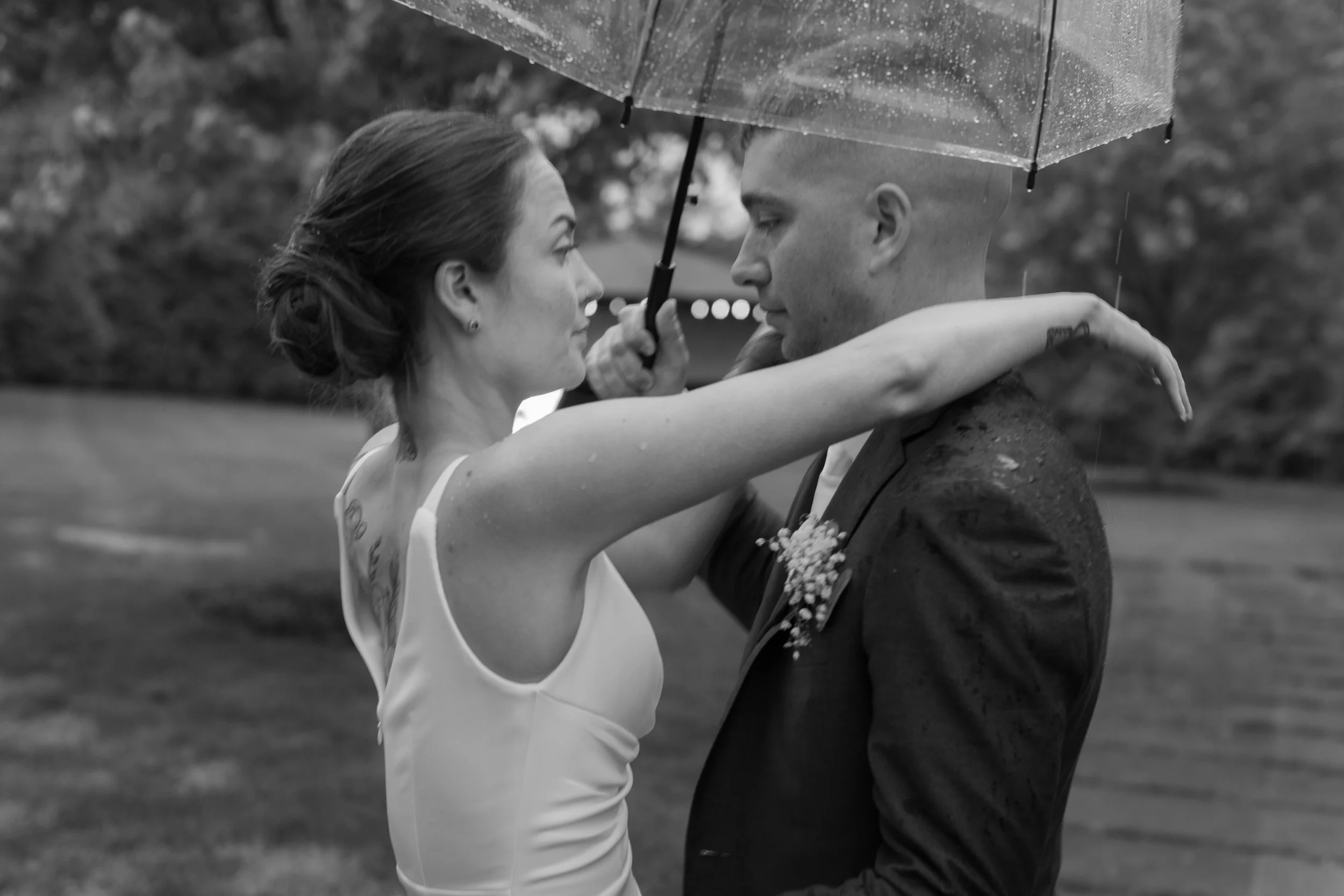 Black and white photo of newly married couple on their wedding day outdoors in the rain
