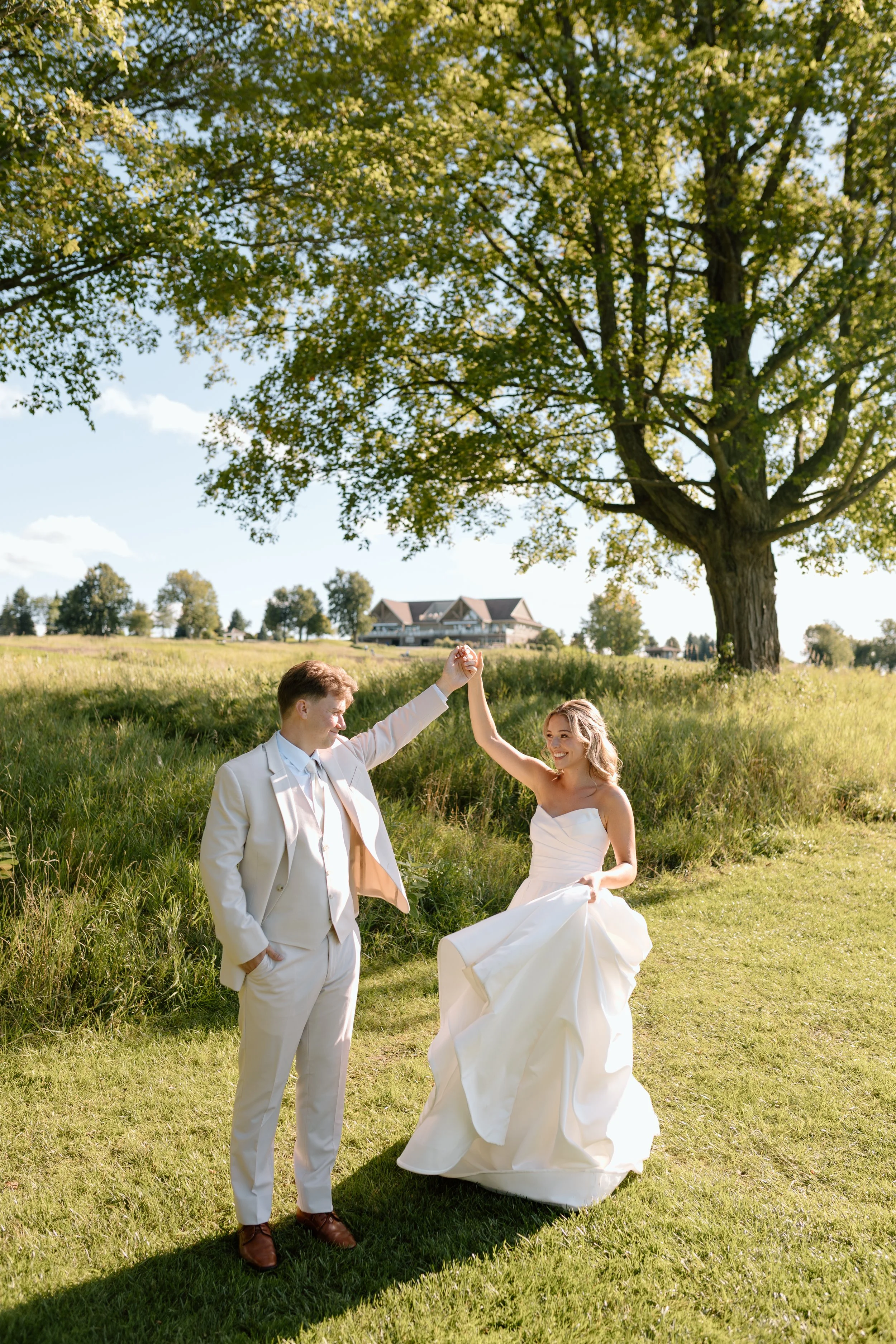 Groom twirling his bride around on a golf course on their wedding day.
