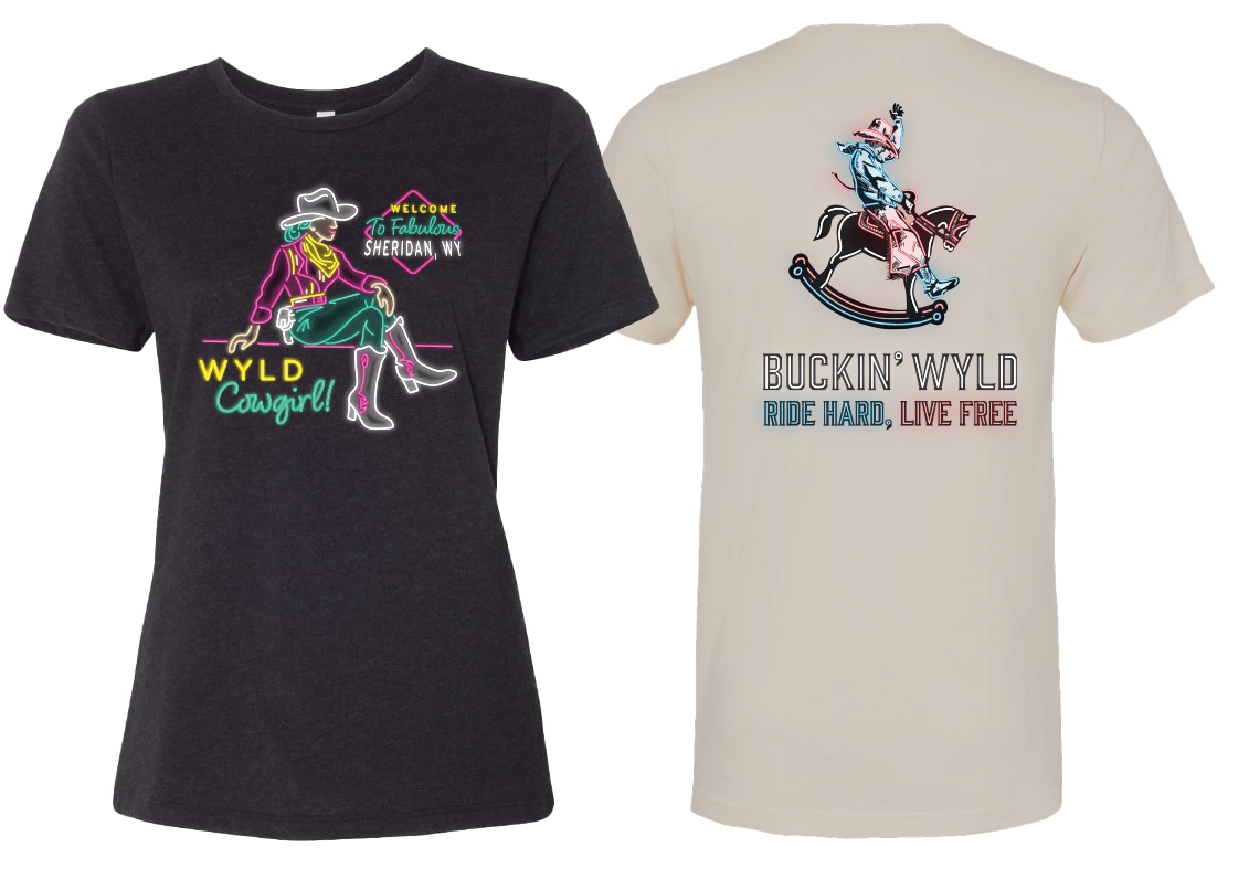 Two T-shirts with southwestern and cowboy theme graphics and text. The black T-shirt features a neon-style illustration of a woman wearing a cowboy hat, boots, and sitting with her legs crossed, with the text "Welcome to Fabulous Sheridan, WY," and "WYLD Cowgirl!" The cream-colored T-shirt has a graphic of a cowboy riding a rocking horse with a red saddle, with the text "Bucking WYLD," and "Ride Hard, Live Free."