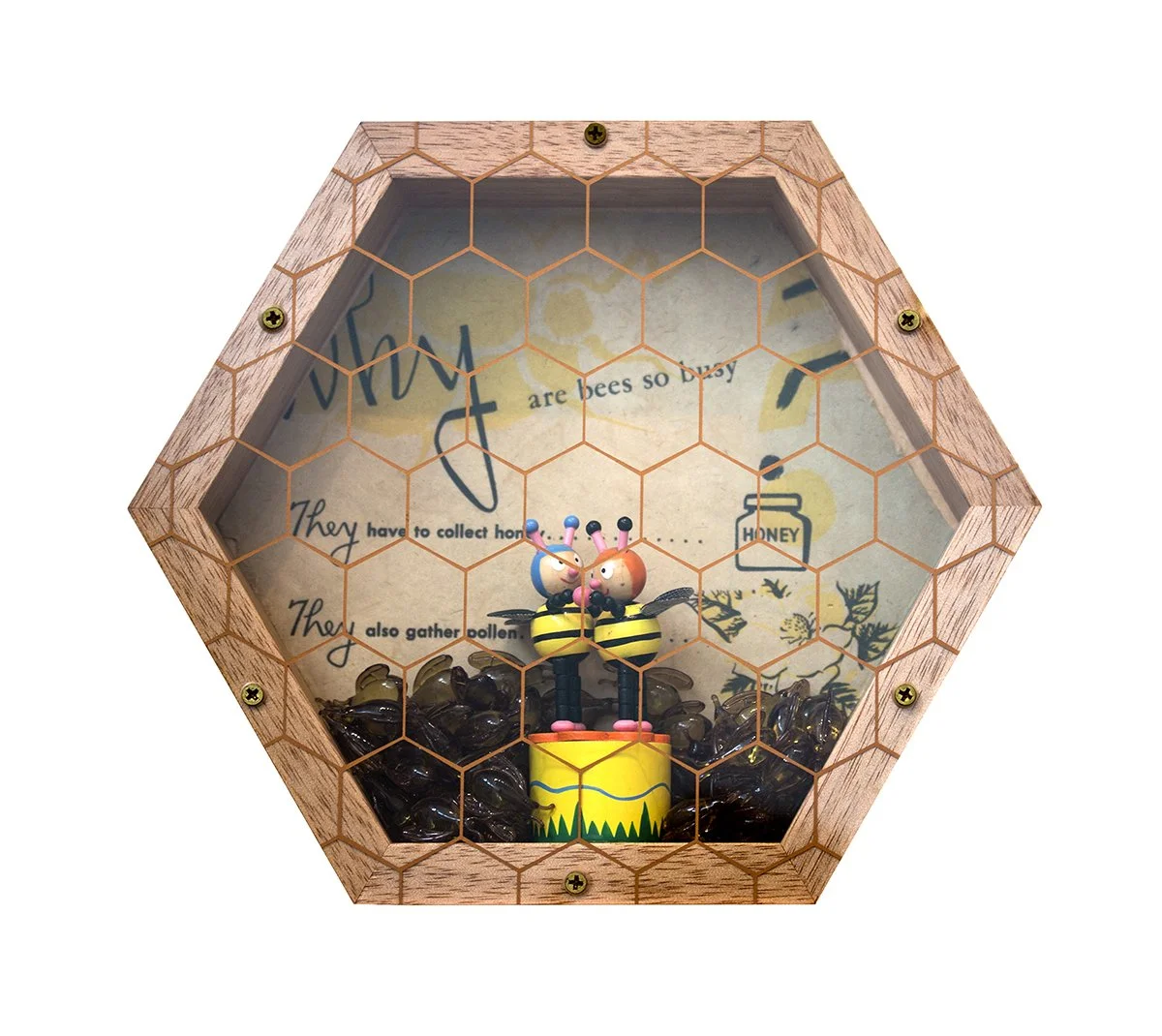 Decorative honey bee display inside a hexagon-shaped wooden box with mesh cover, containing bee figurines on a honey pot surrounded by honeycomb-patterned material and illustration background.