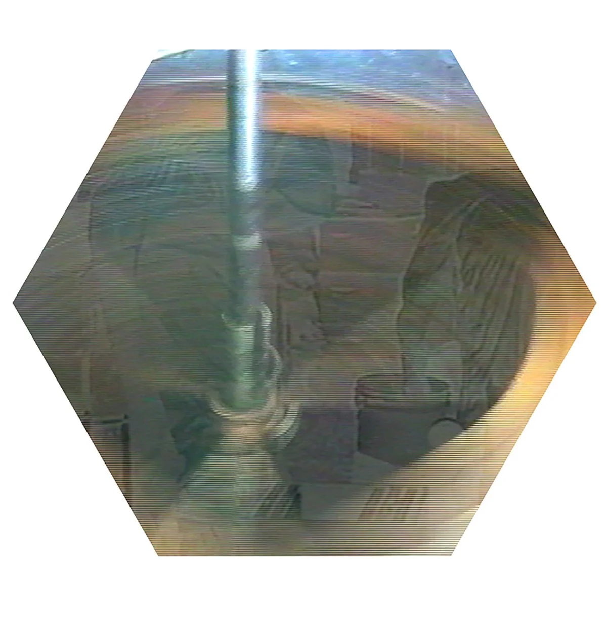 A metallic device with a vertical rod and a base, possibly a laboratory or industrial piece of equipment, viewed through a hexagonal frame with a transparent surface showing the equipment underneath.