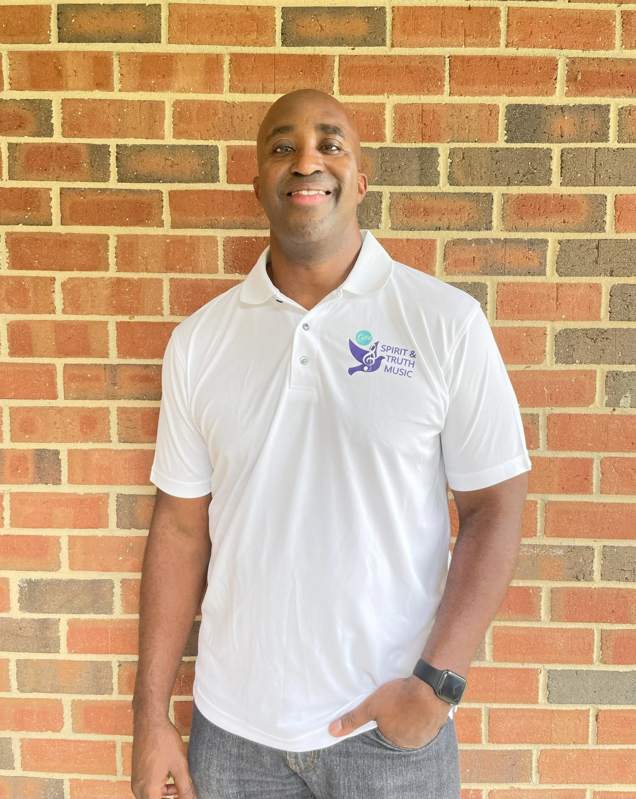 man in white polo standing in front of brick wall