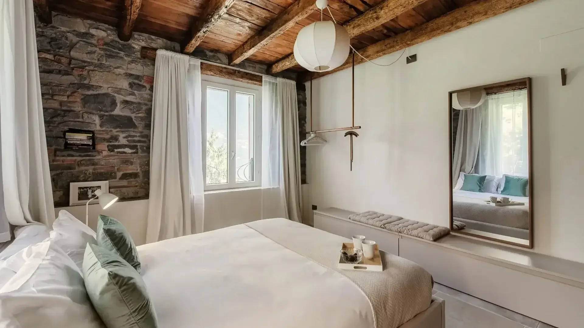 Rustic bedroom with stone walls and lake view