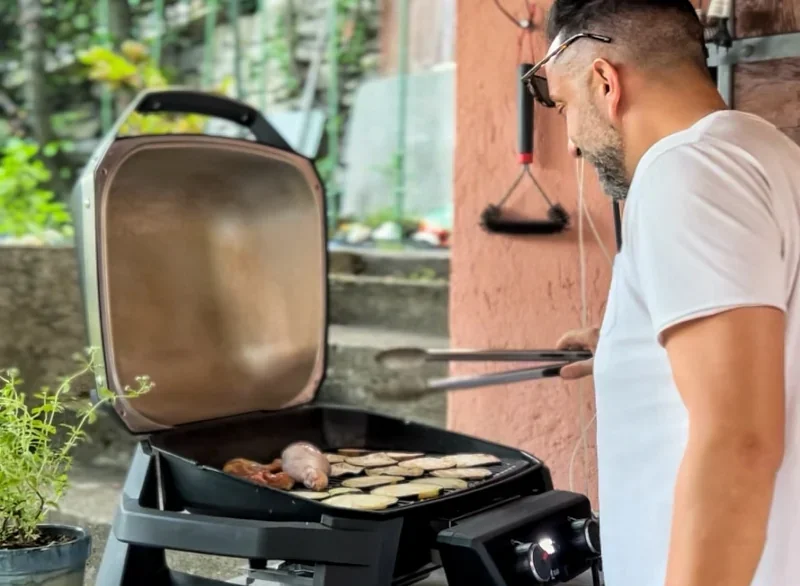 Mannen die barbecueën met een elektrische Weber-barbecue