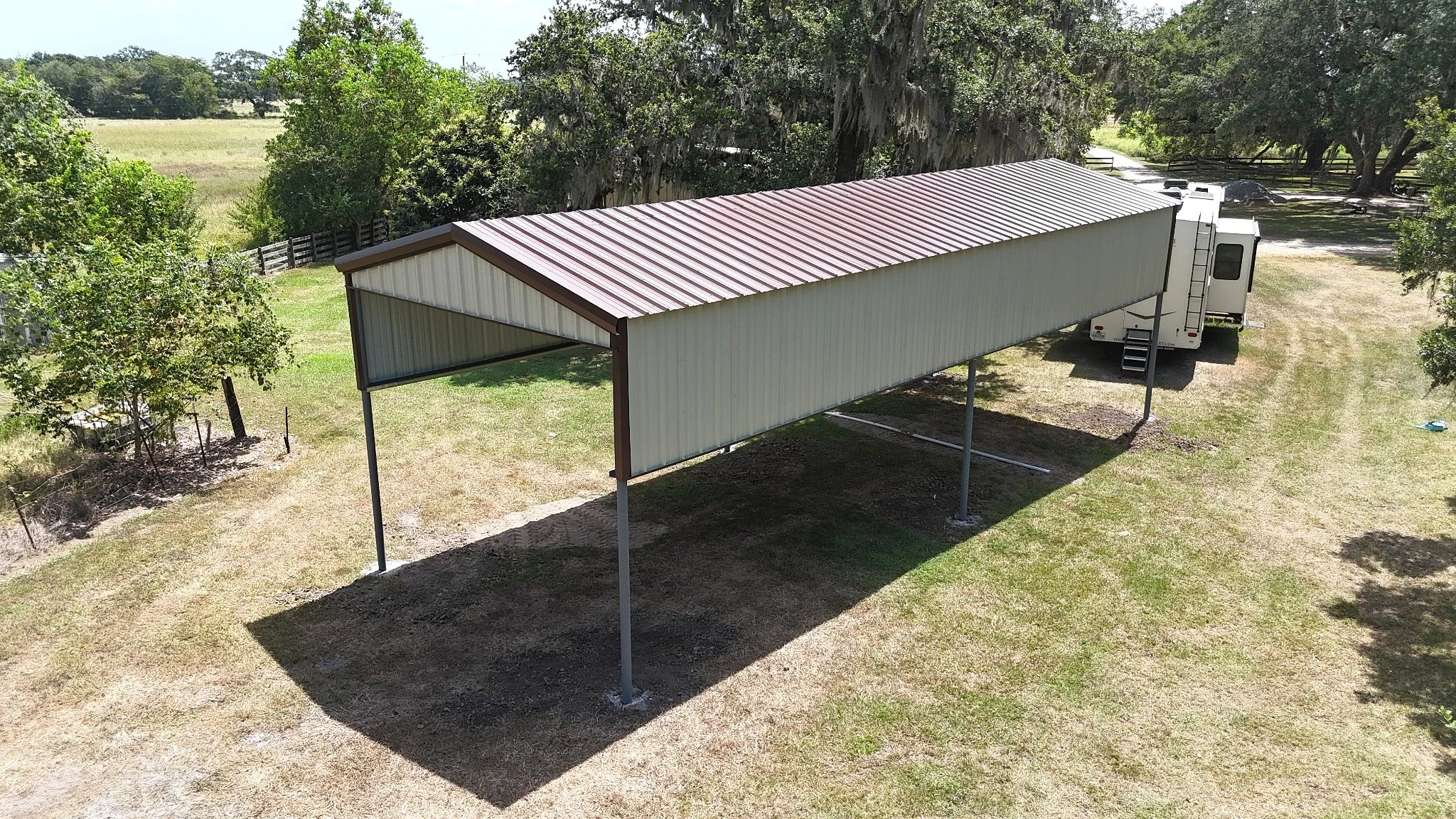 Elevated view showing the RV cover’s 26-gauge R-panel roof and siding, contrasting trim, and open design for easy entry and ventilation.