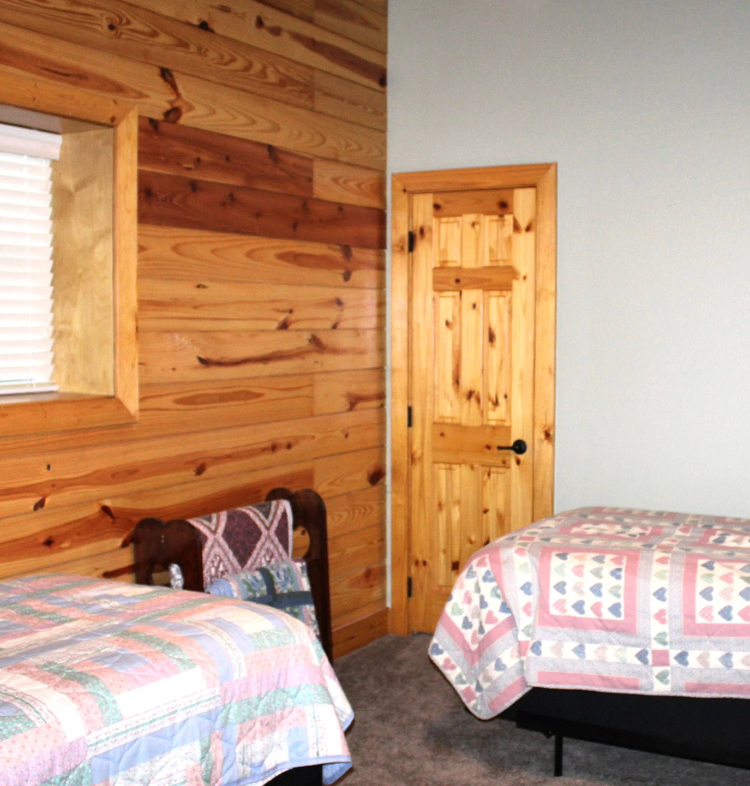 Guest bedroom inside barndominium with solid pine shiplap wall and solid pine door.