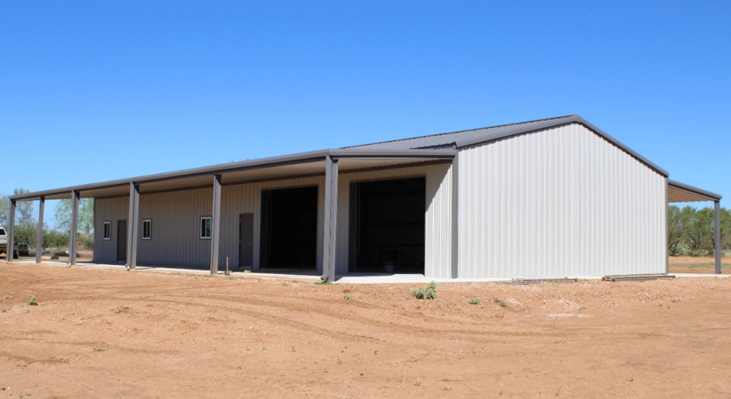 Custom barndominium with 2 roll up shop doors for storing hunting equipment and vehicles.