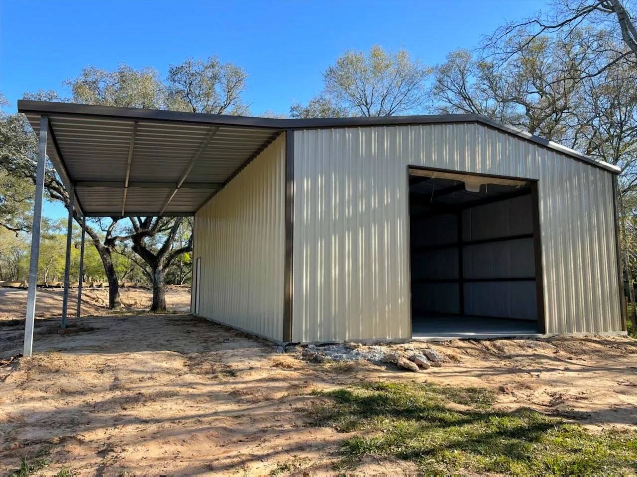 Beige metal garage with brown trim, side lean-to for RV storage in Brenham Texas.