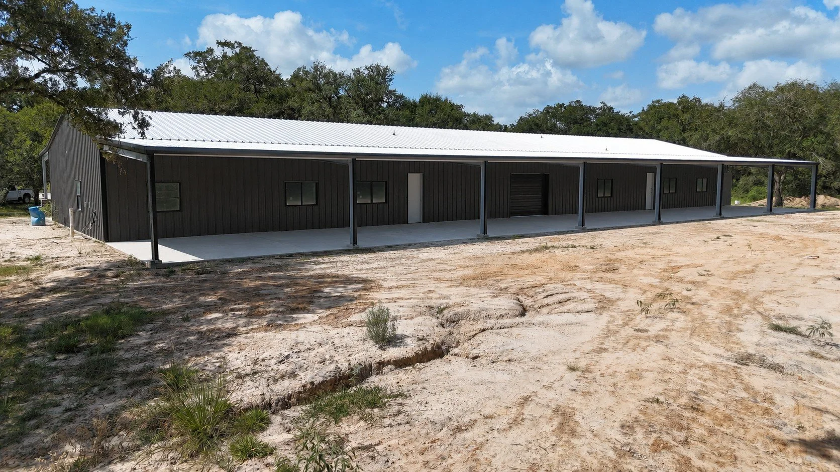 Full view of the spacious covered rear porch extending across the dual-residence barndominium in Damon, Texas.